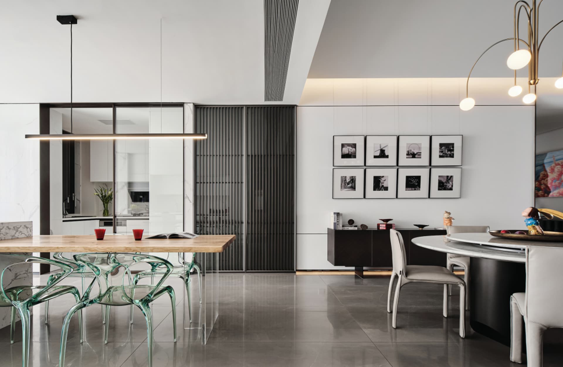 Modern dining room featuring sleek, transparent chairs, a wooden table, and contemporary artwork.