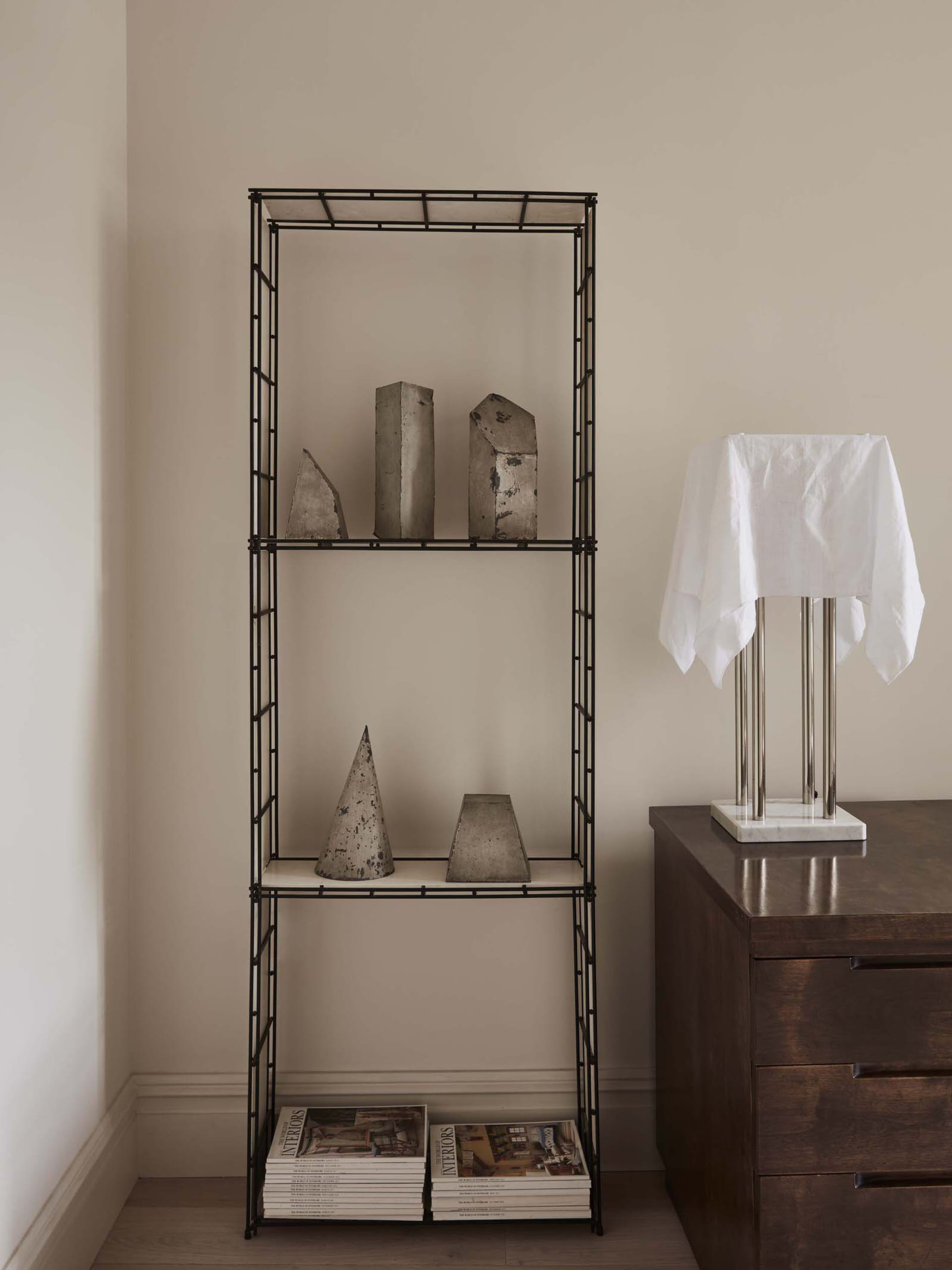 A minimalist metal shelving unit displaying abstract sculptures.