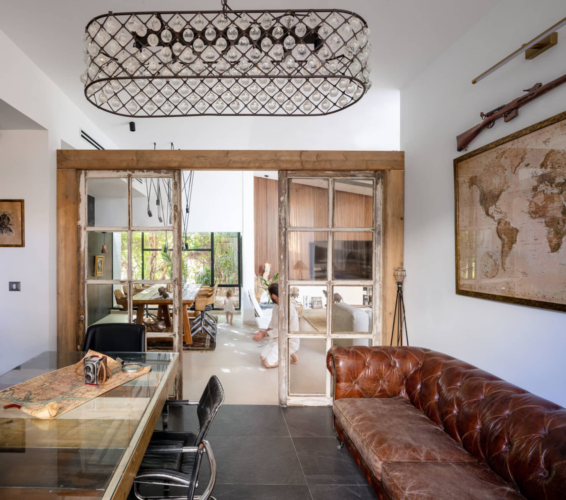 A spacious, open-concept living room with industrial design elements, featuring woven-wood paneling, a large leather sofa, an