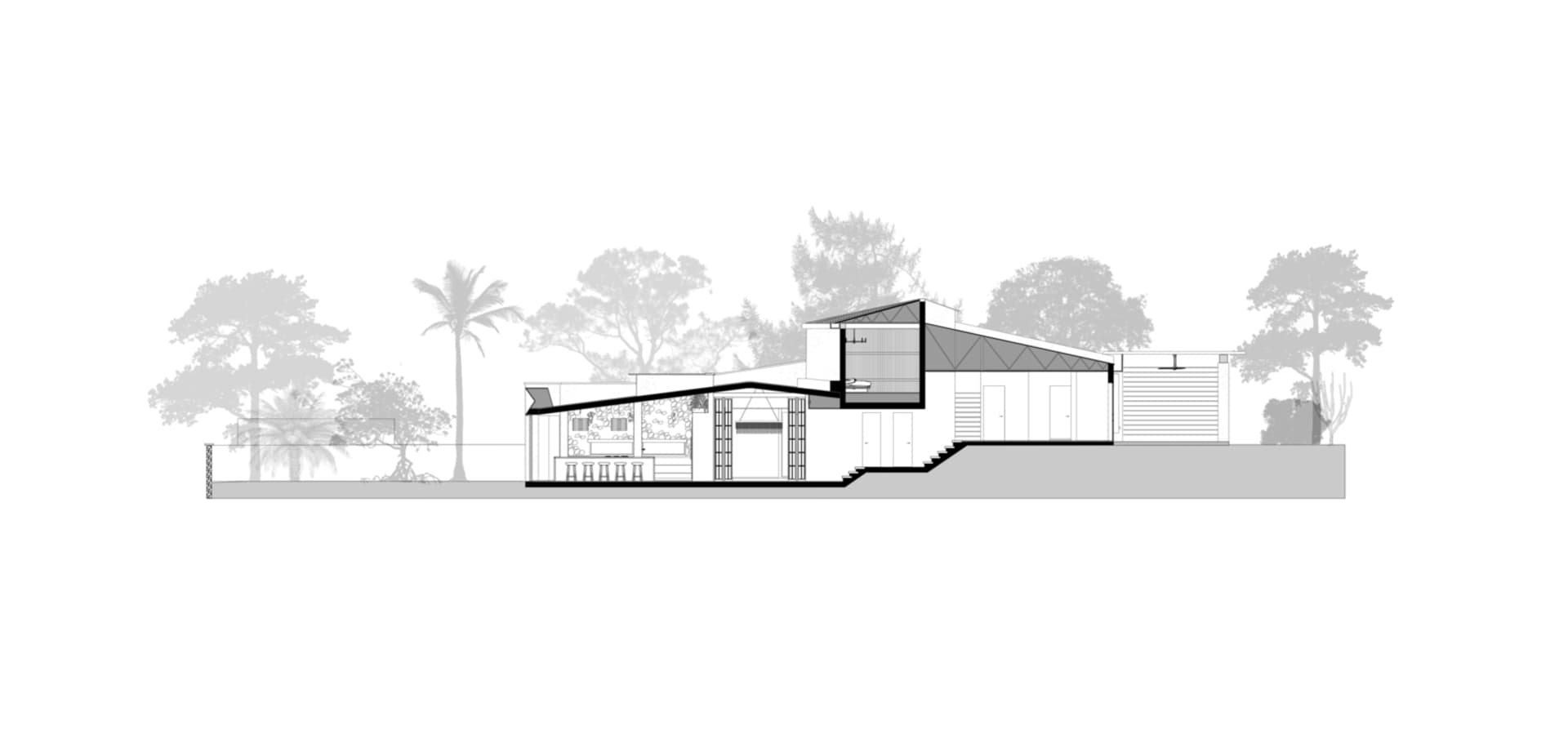 Modern house with concrete exterior and large windows against a tree-lined background.