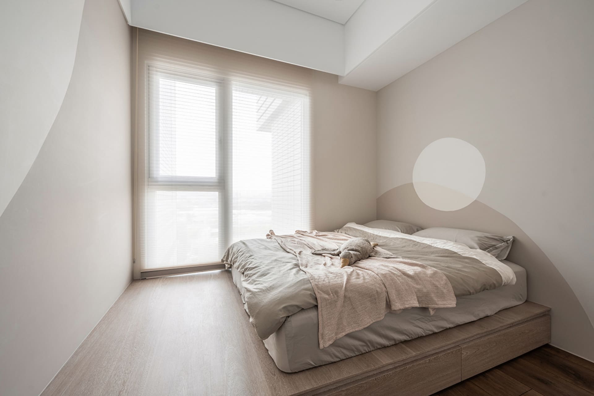 Modern minimalist bedroom featuring a light wood bed frame and soft, neutral bedding.