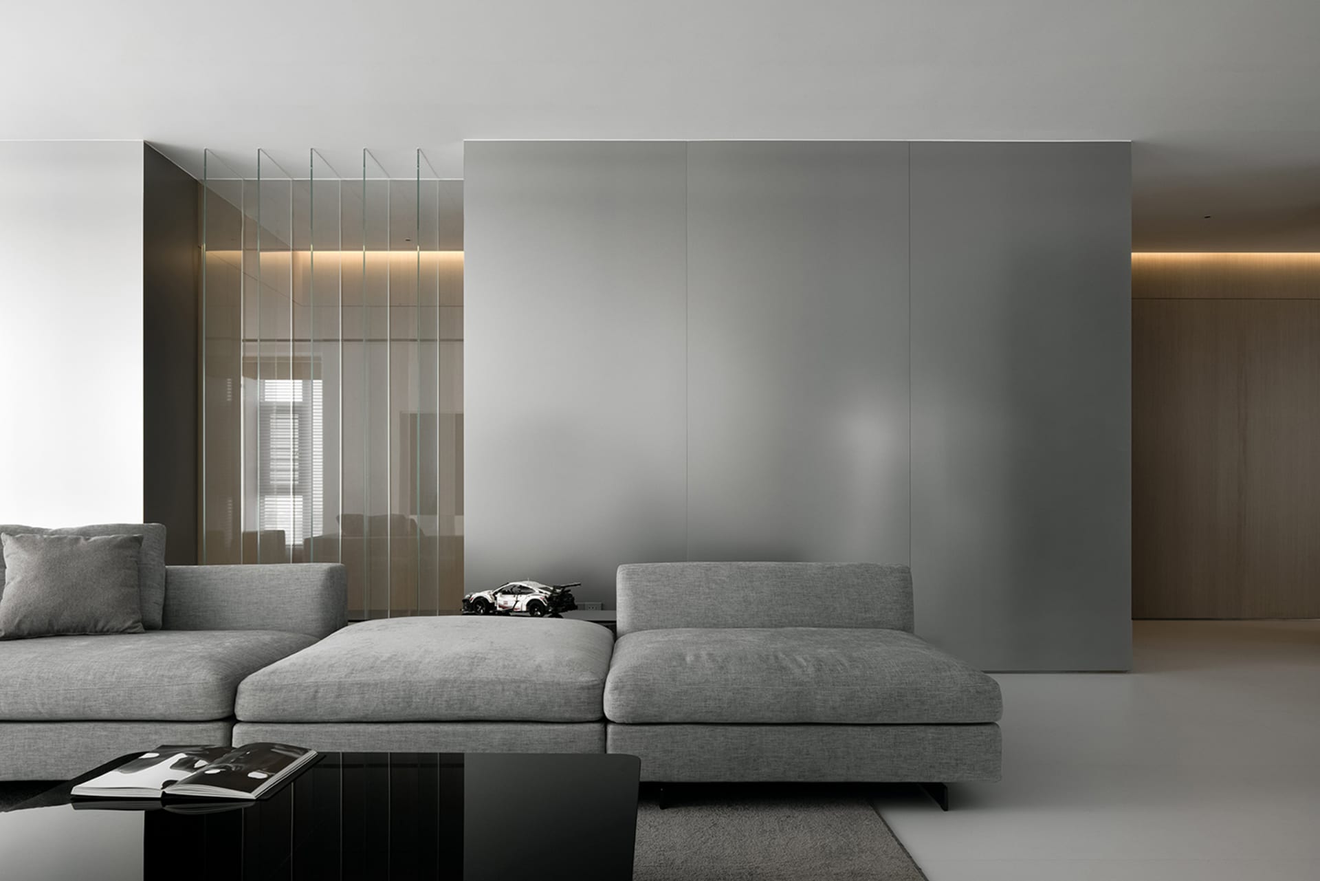 A modern industrial living room featuring grey fabric furniture, minimalist decor, and a sleek, glossy floor.