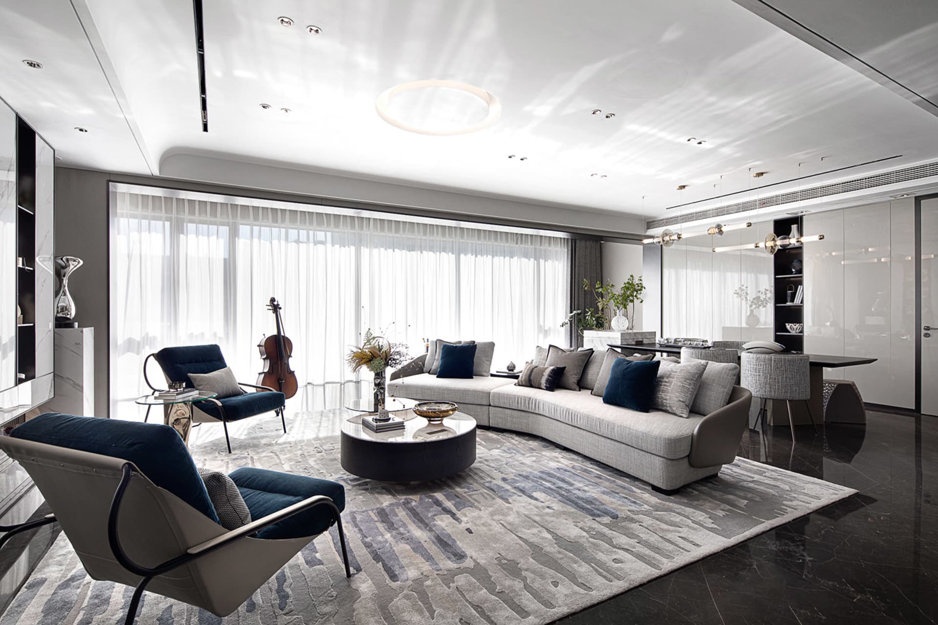 Contemporary living room with modern interior design elements, featuring a curved sofa, dark armchairs, and large windows.