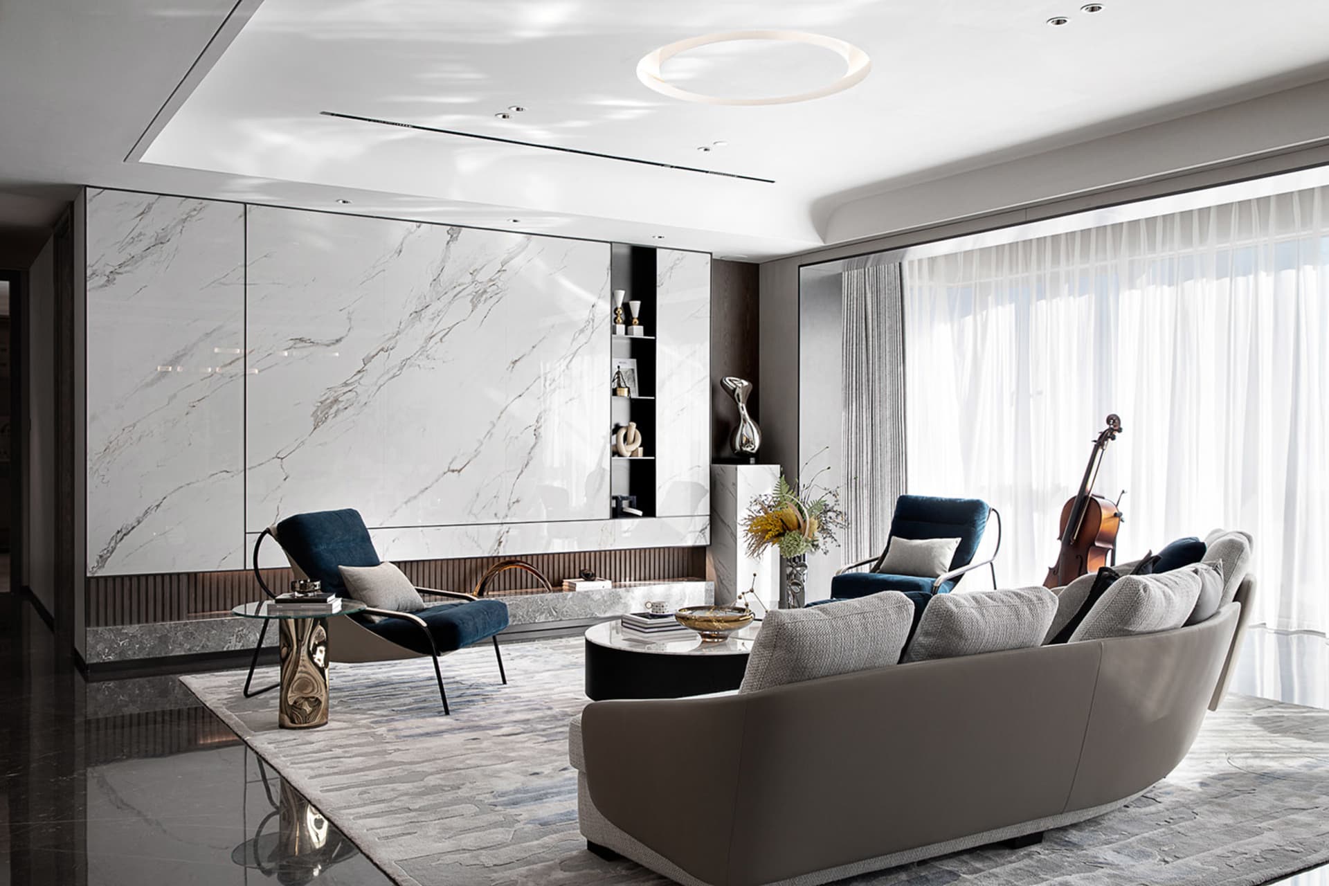Modern living room featuring marble walls, leather furniture, and glass decor.