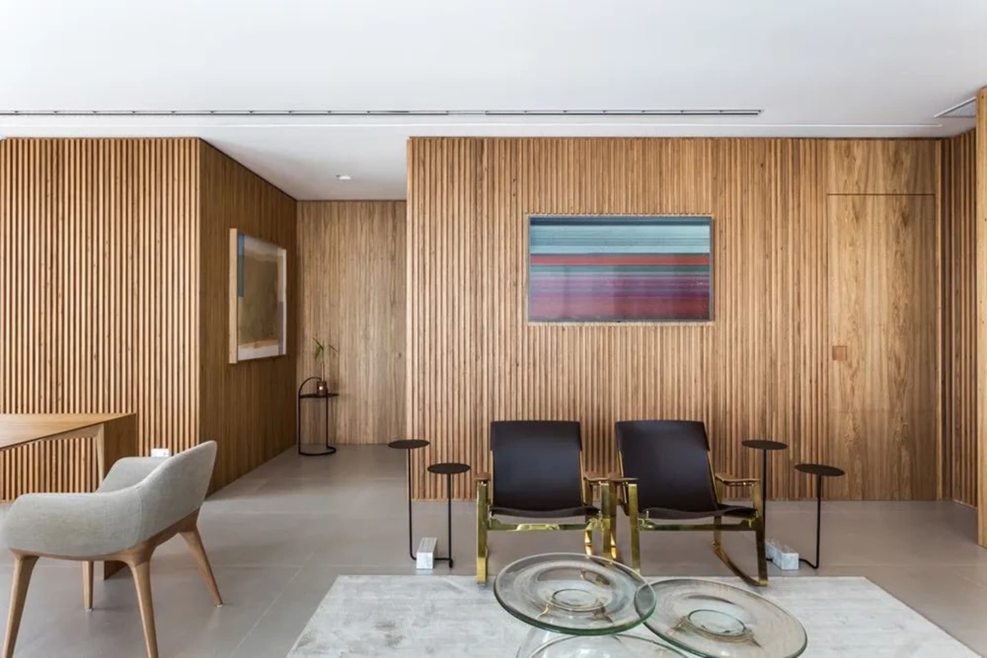 A modern living room featuring a wooden wall, glass coffee tables, and contemporary furniture.