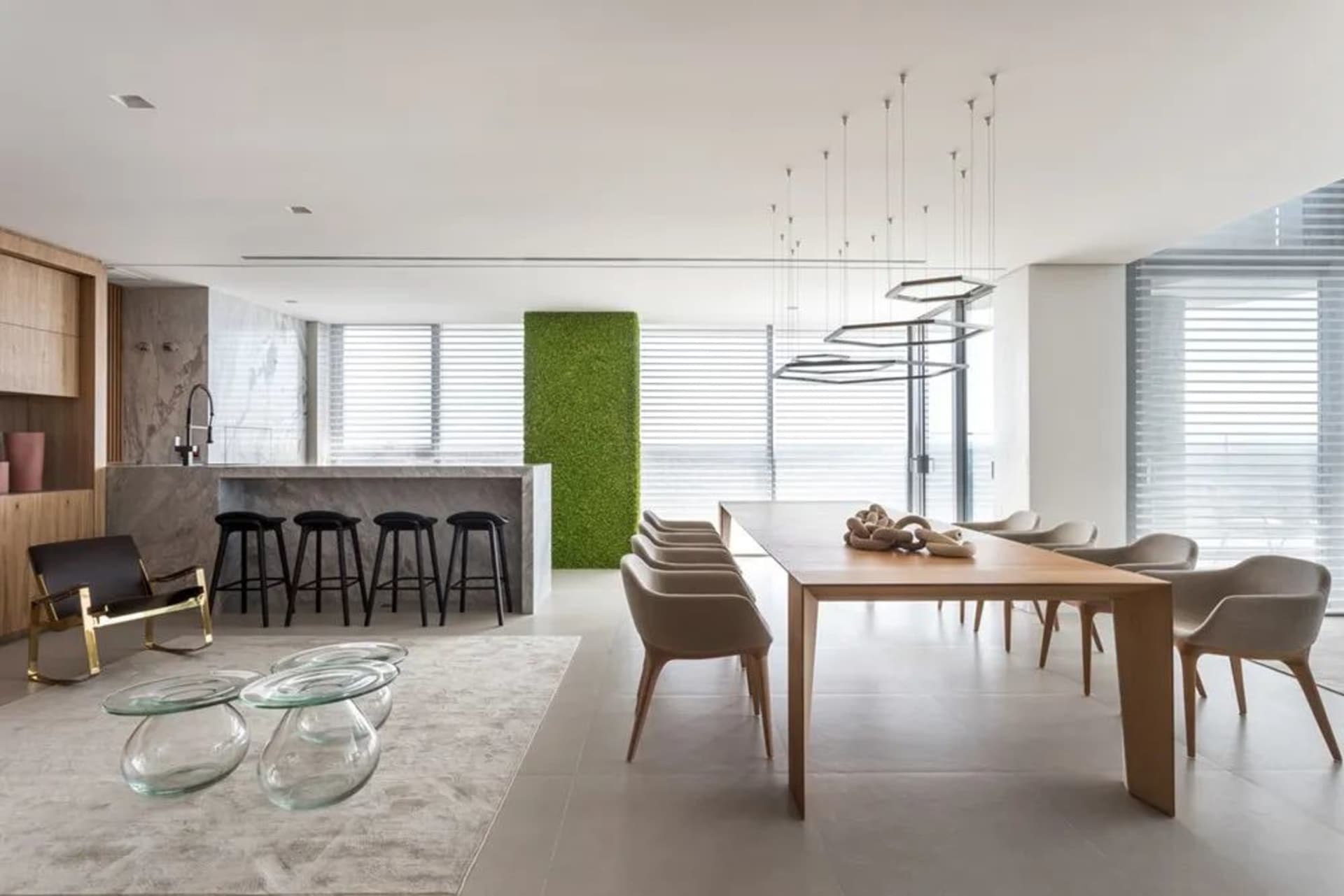 Modern residential dining room featuring wooden table, glass chairs, marble countertop, and upholstered seating.