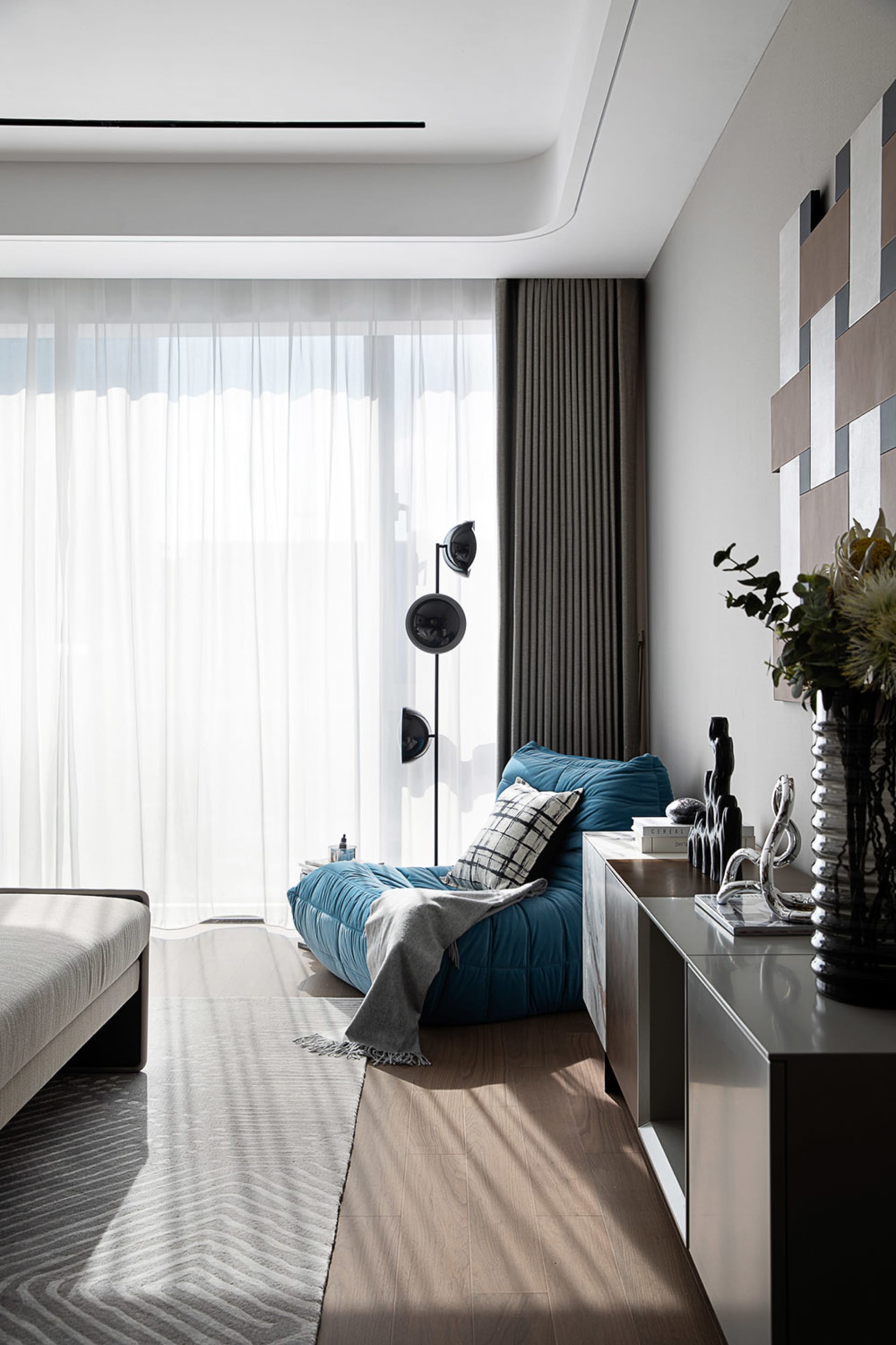 A modern minimalist living room featuring a comfortable fabric seating area with a metal frame, a wooden coffee table, and mi