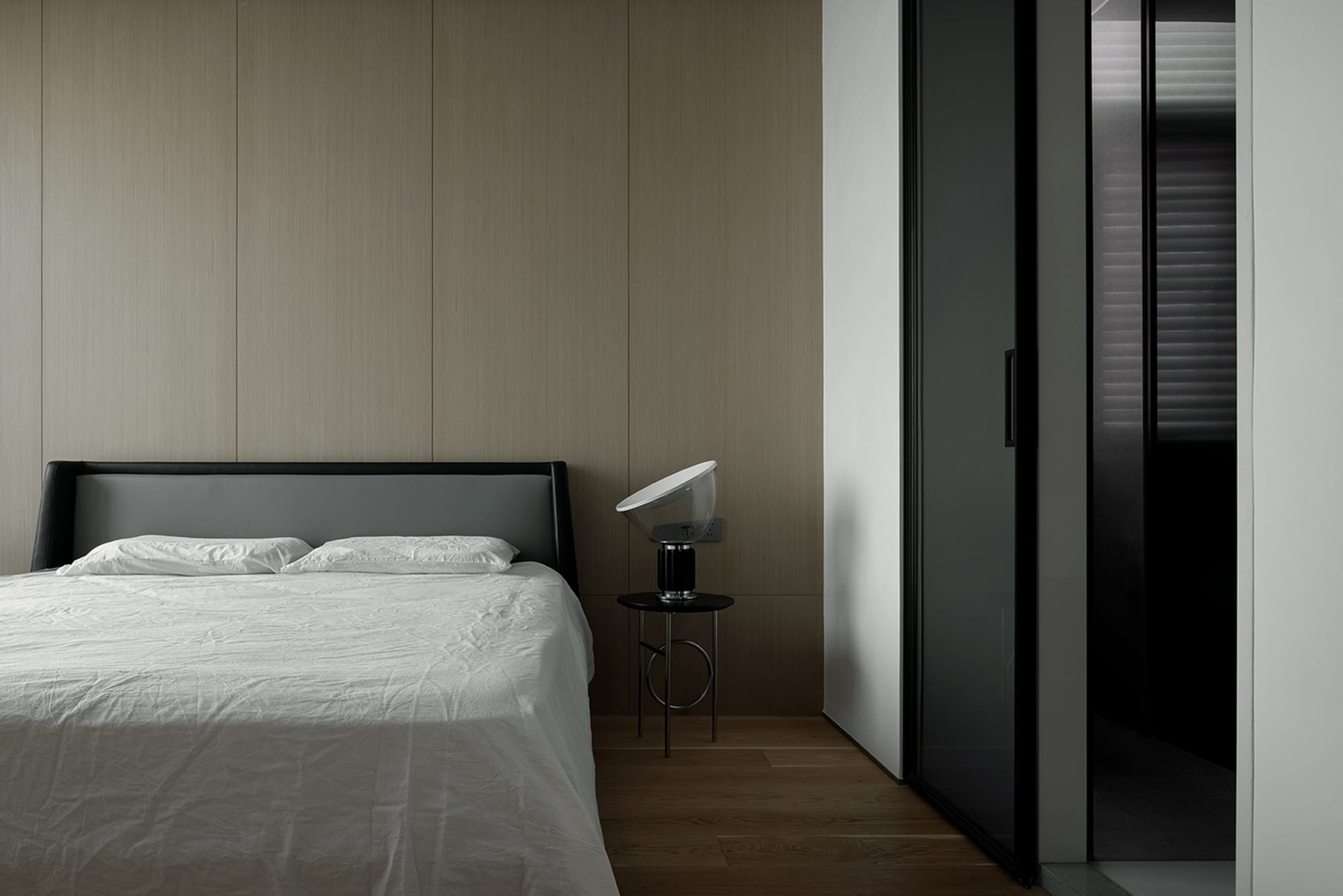 Minimalist bedroom with a wooden headboard and floor-to-ceiling wood panels.