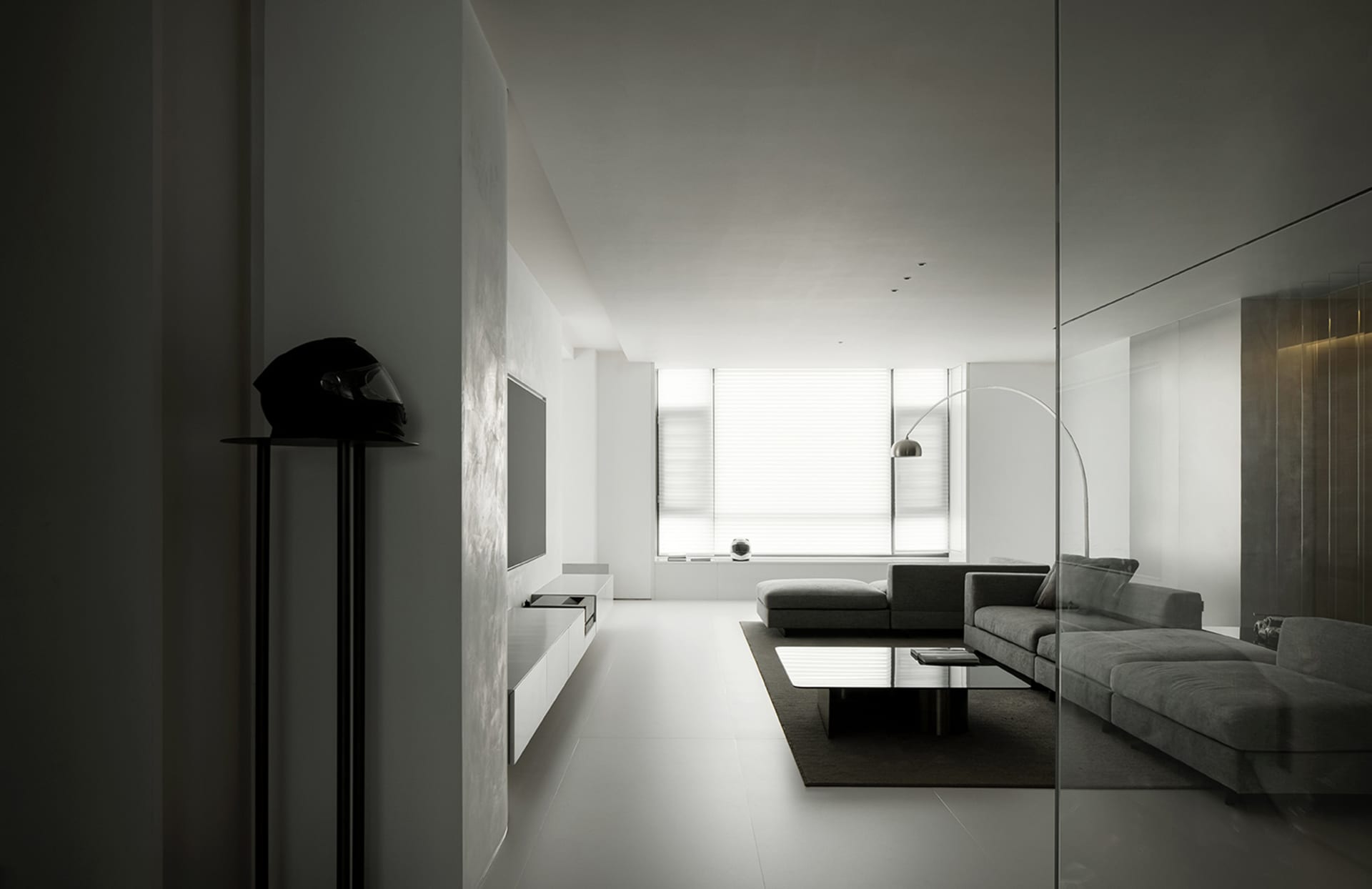 Modern minimalist living room with concrete floor, glass walls, and a sleek, grey sofa.