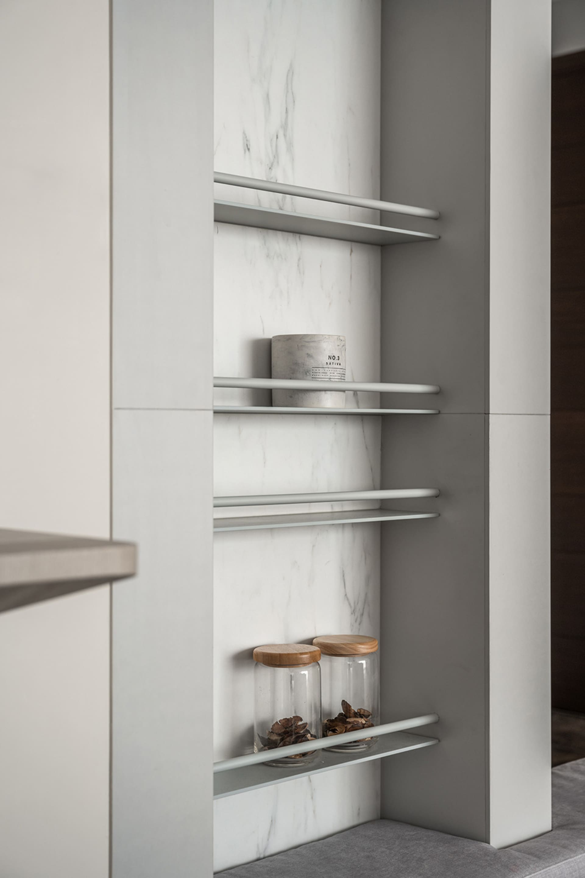A modern minimalist kitchen with sleek, white marble countertops and shelves.