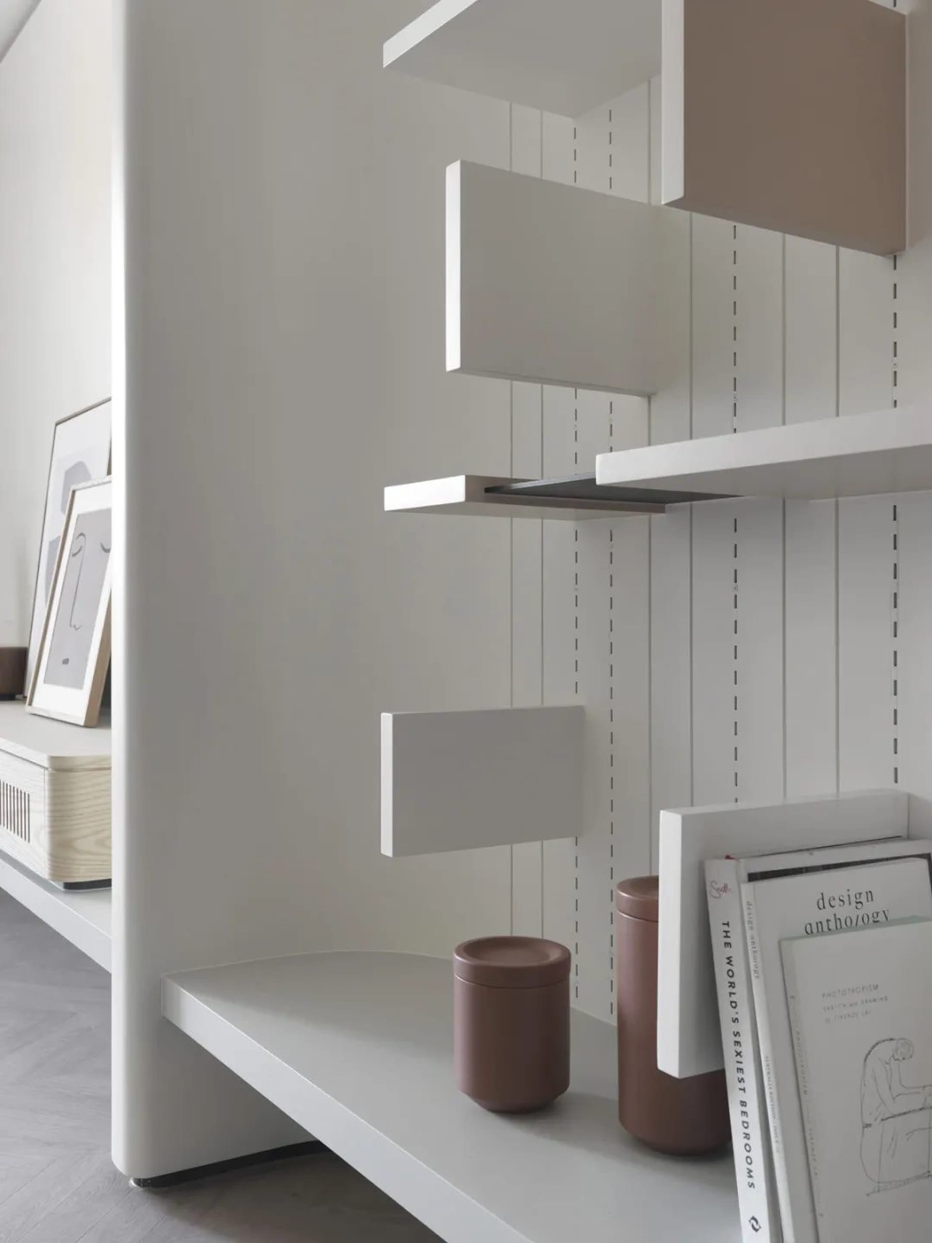 A minimalist bookshelf made of white wood with various shelves and objects.