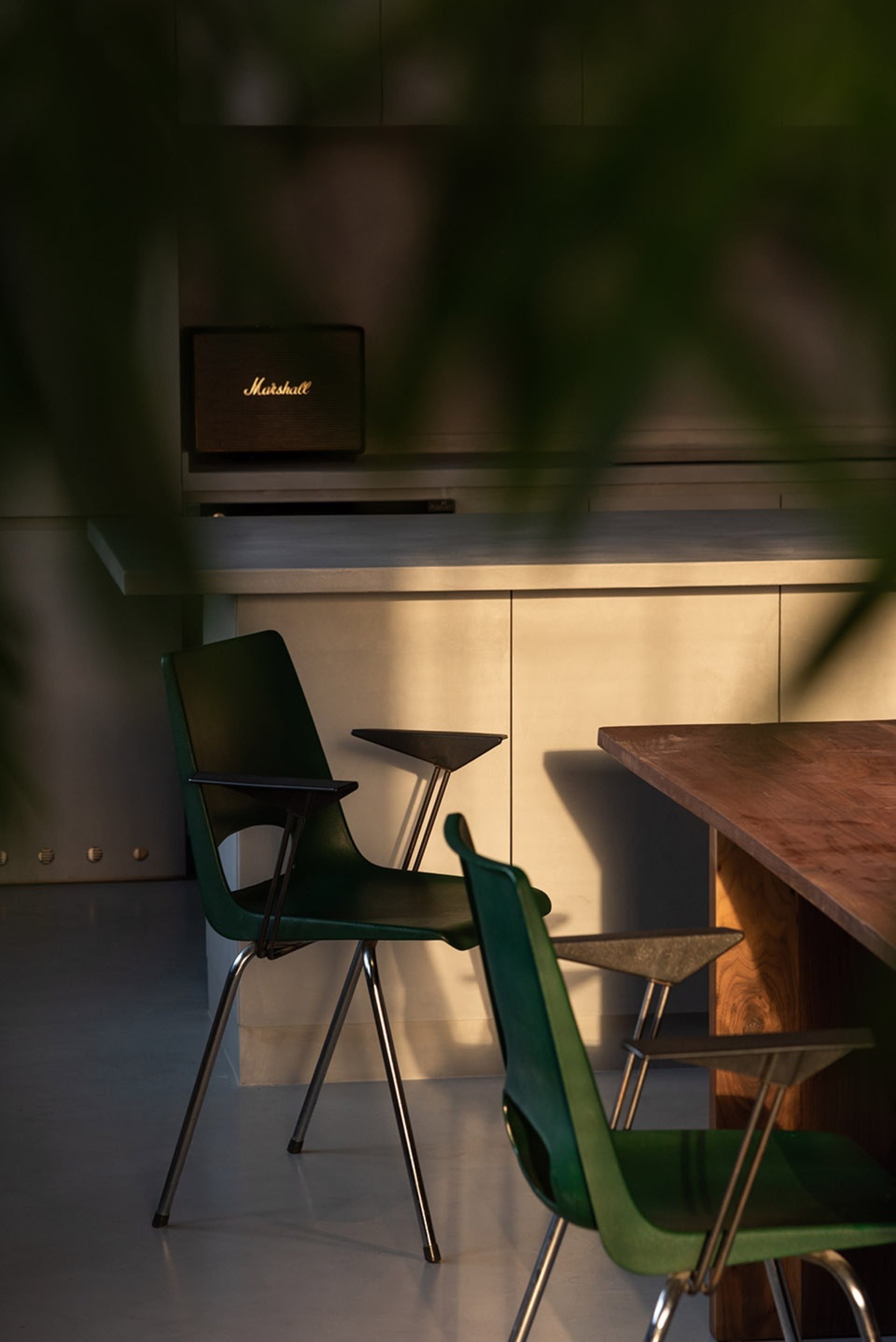 Industrial-style office space featuring a wooden table and green chairs.