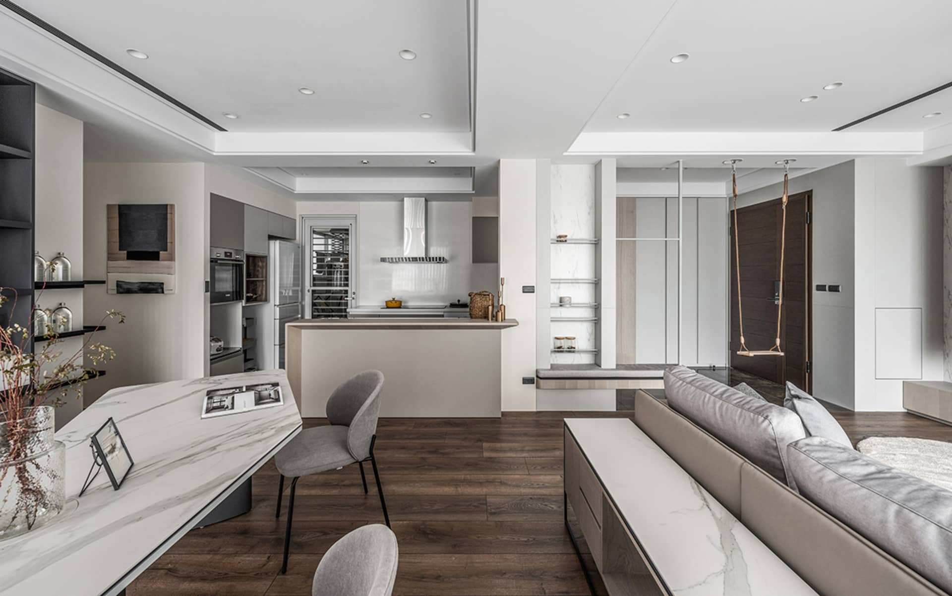 A modern living room with a kitchen counter featuring wood, marble, and metal materials.