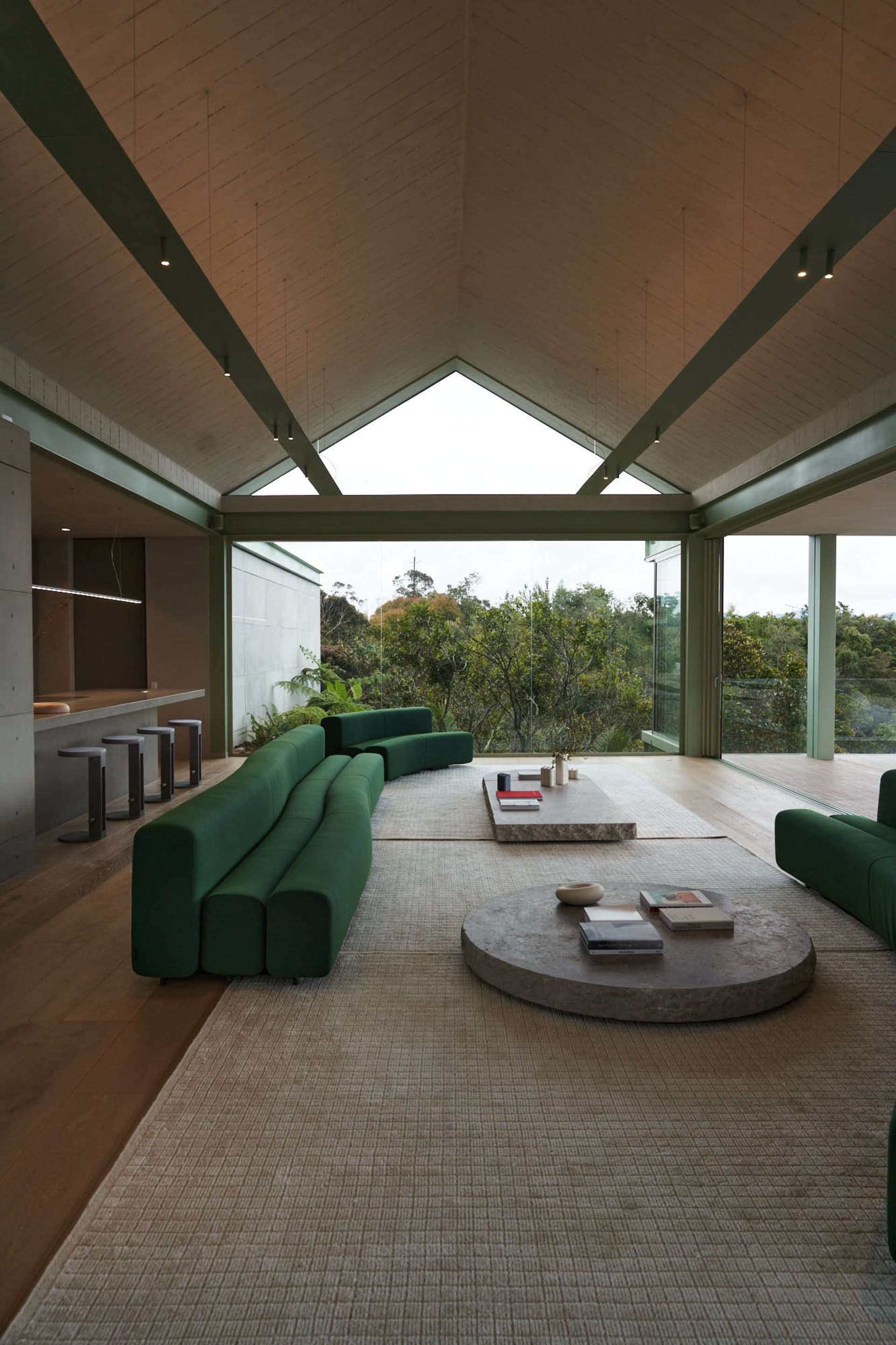 A modern living room with green fabric seating, wooden accents, and concrete elements.