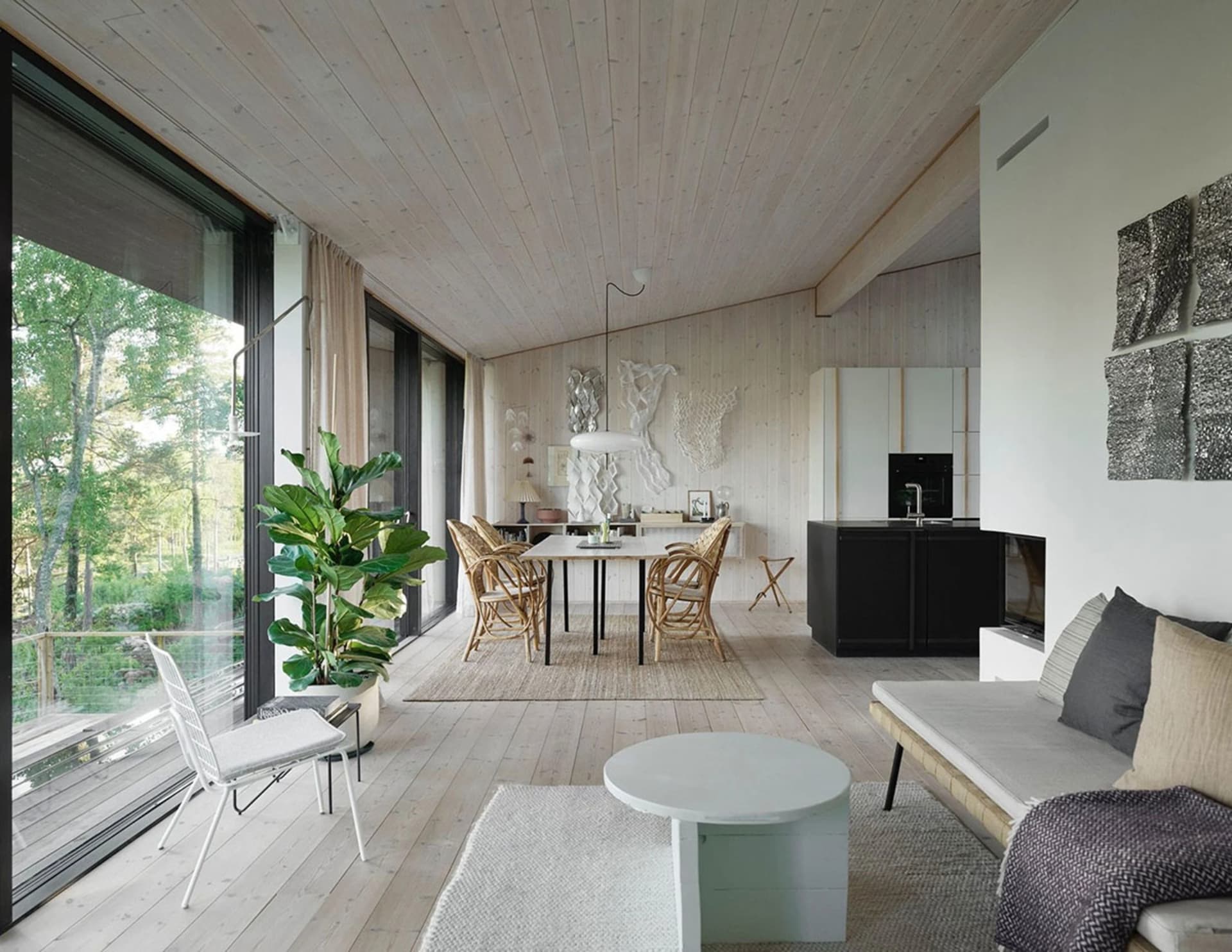 A minimalist living room featuring wood flooring and walls, with a white sofa and circular coffee table.