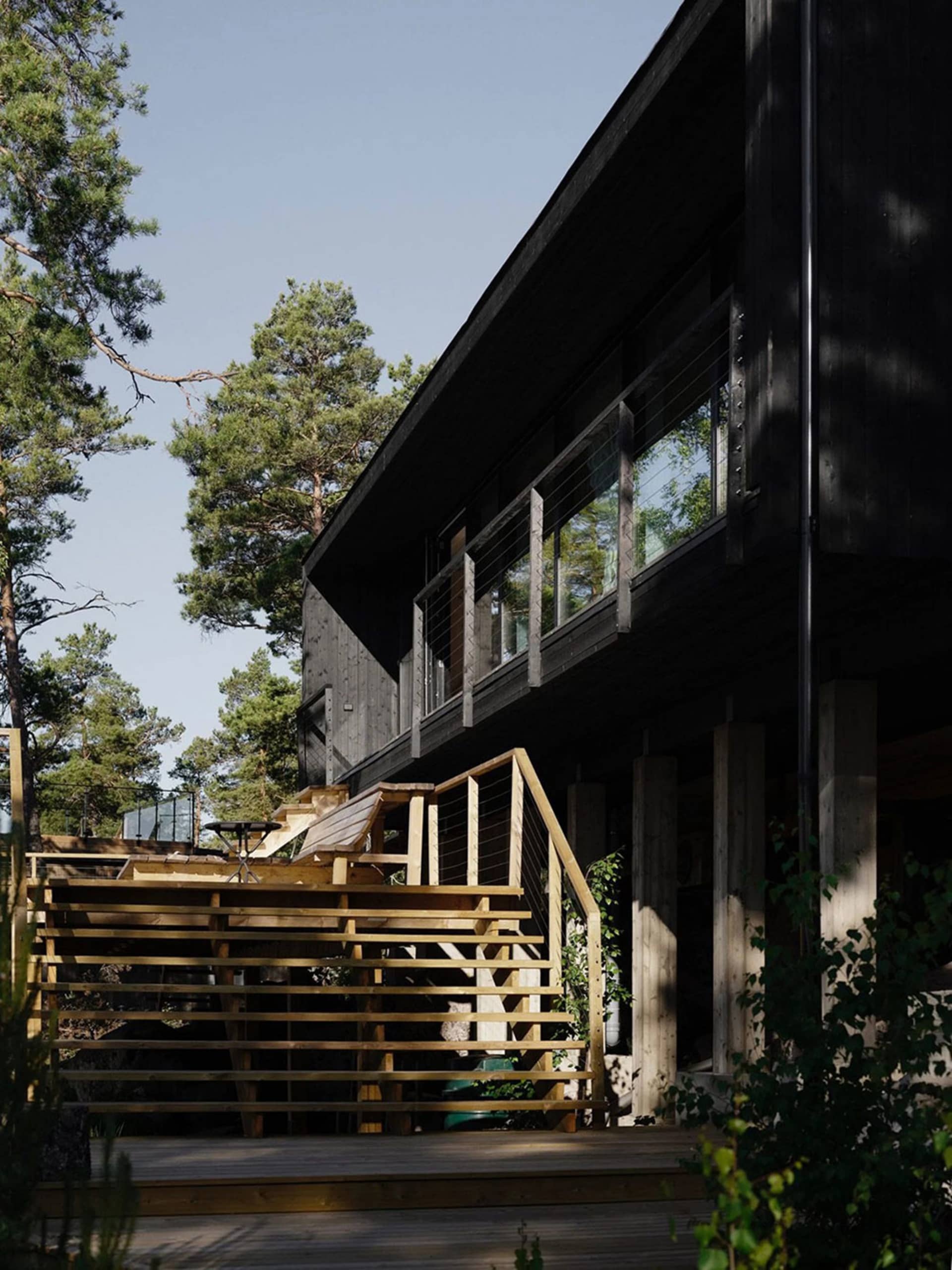 現代極簡住宅建築，外牆採用木質材料，搭配玻璃窗與混凝土基座。