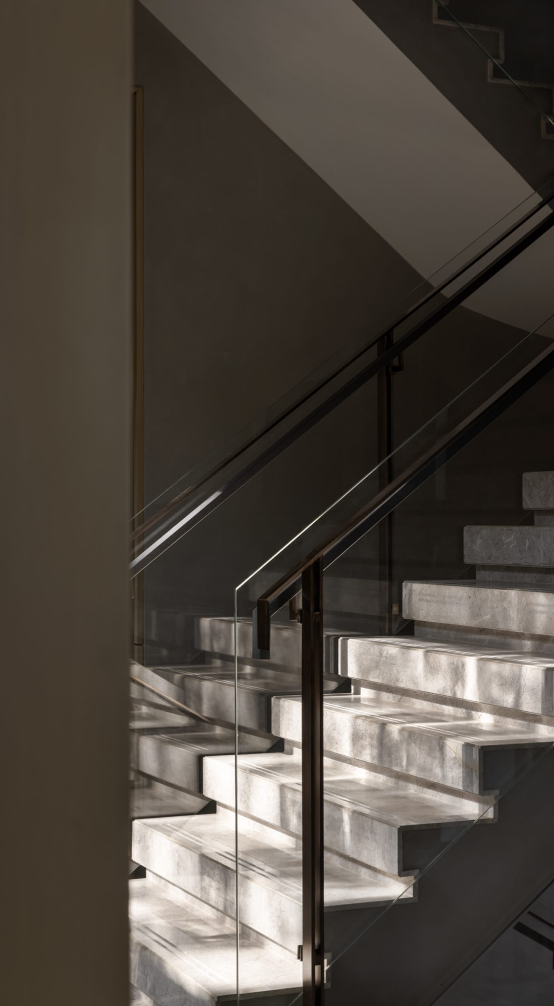 A modern marble staircase with glass railings.