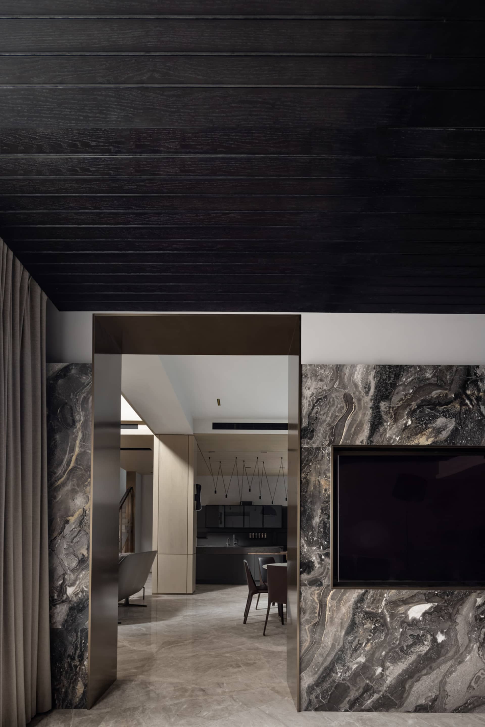 Modern, minimalist kitchen area with marble countertops and dark wood accents.