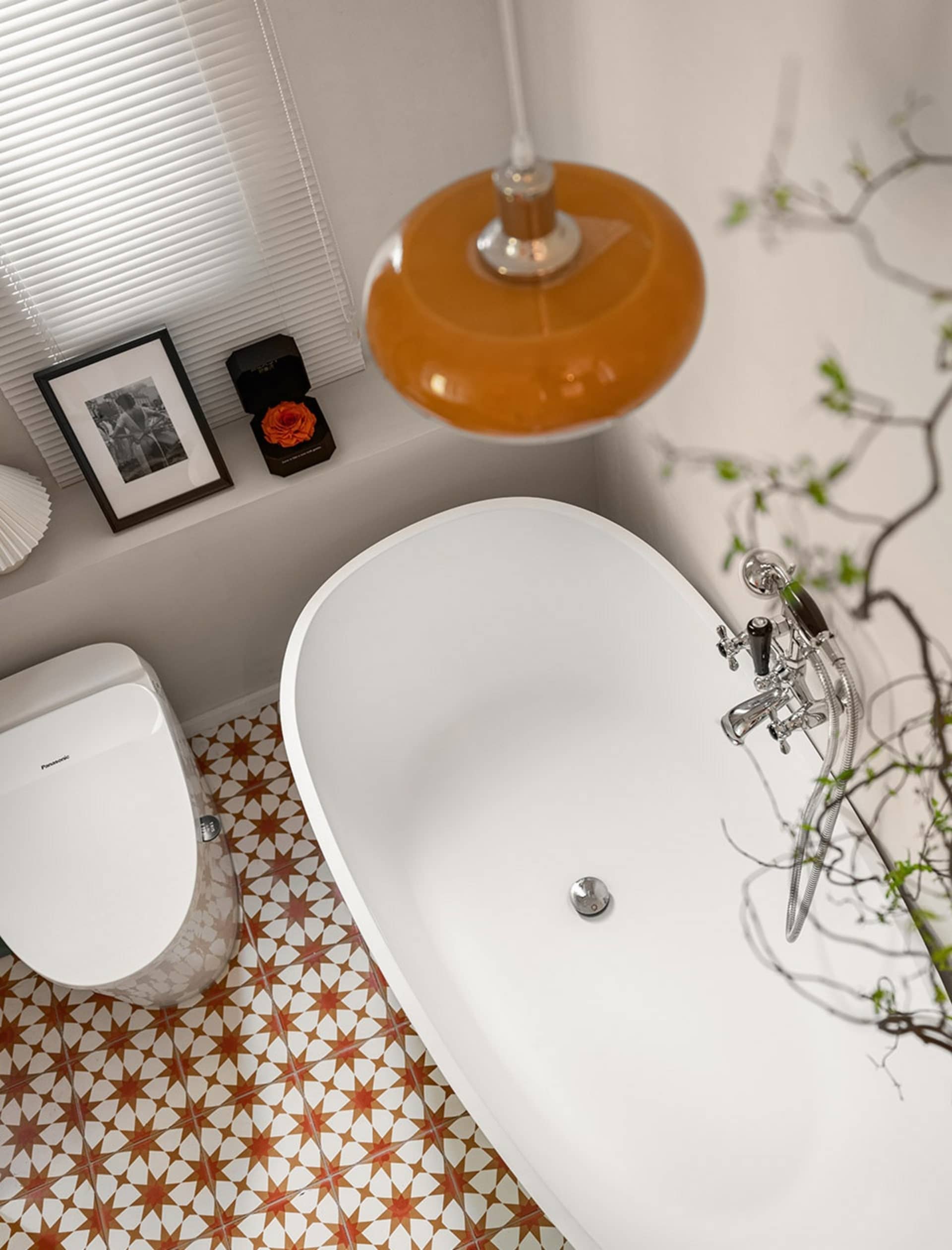 Modern bathroom featuring a freestanding bathtub, toilet, and terracotta and white porcelain tile flooring.