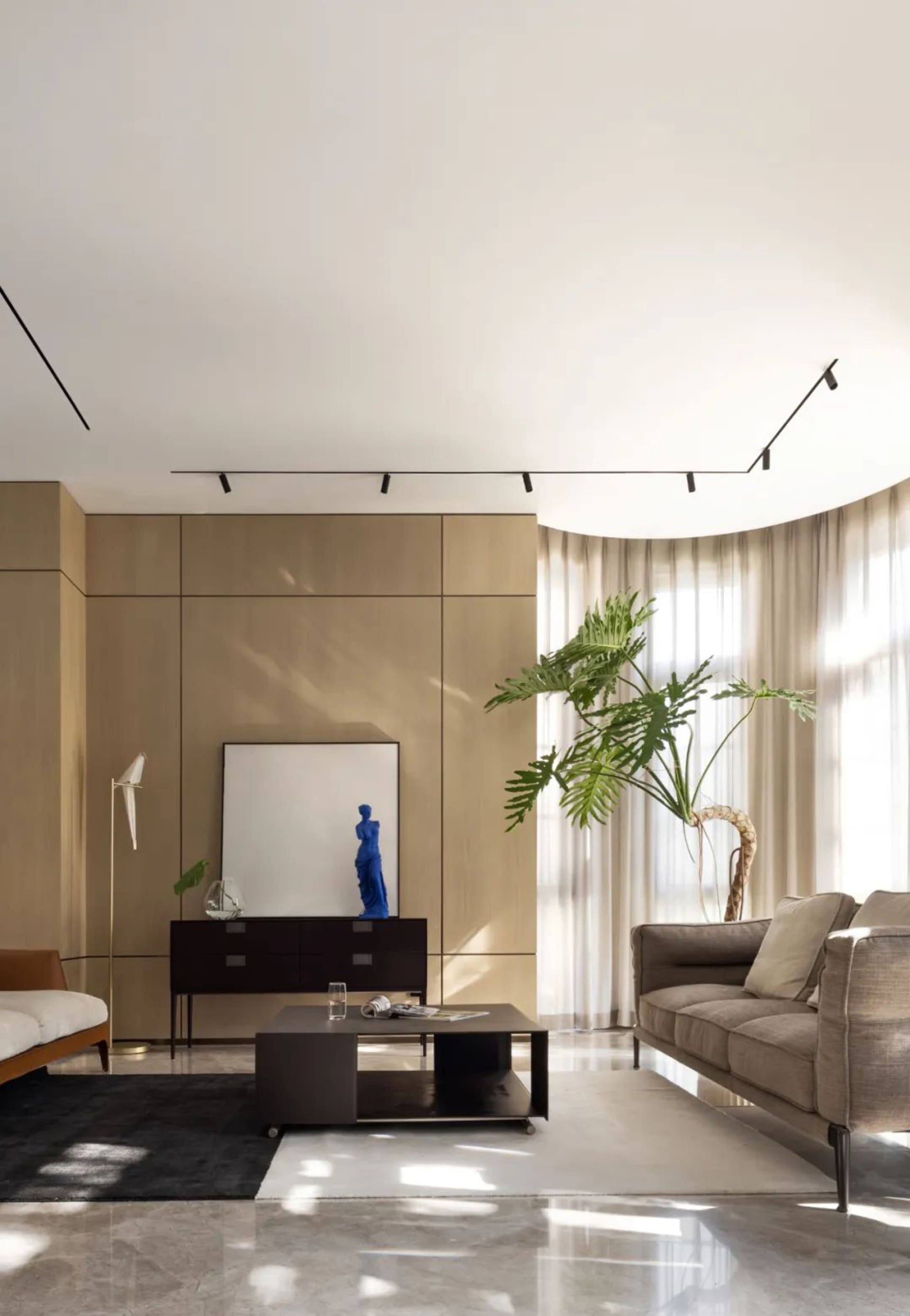 A modern living room with taupe-colored wood paneling, large glass windows, and a comfortable leather sofa.