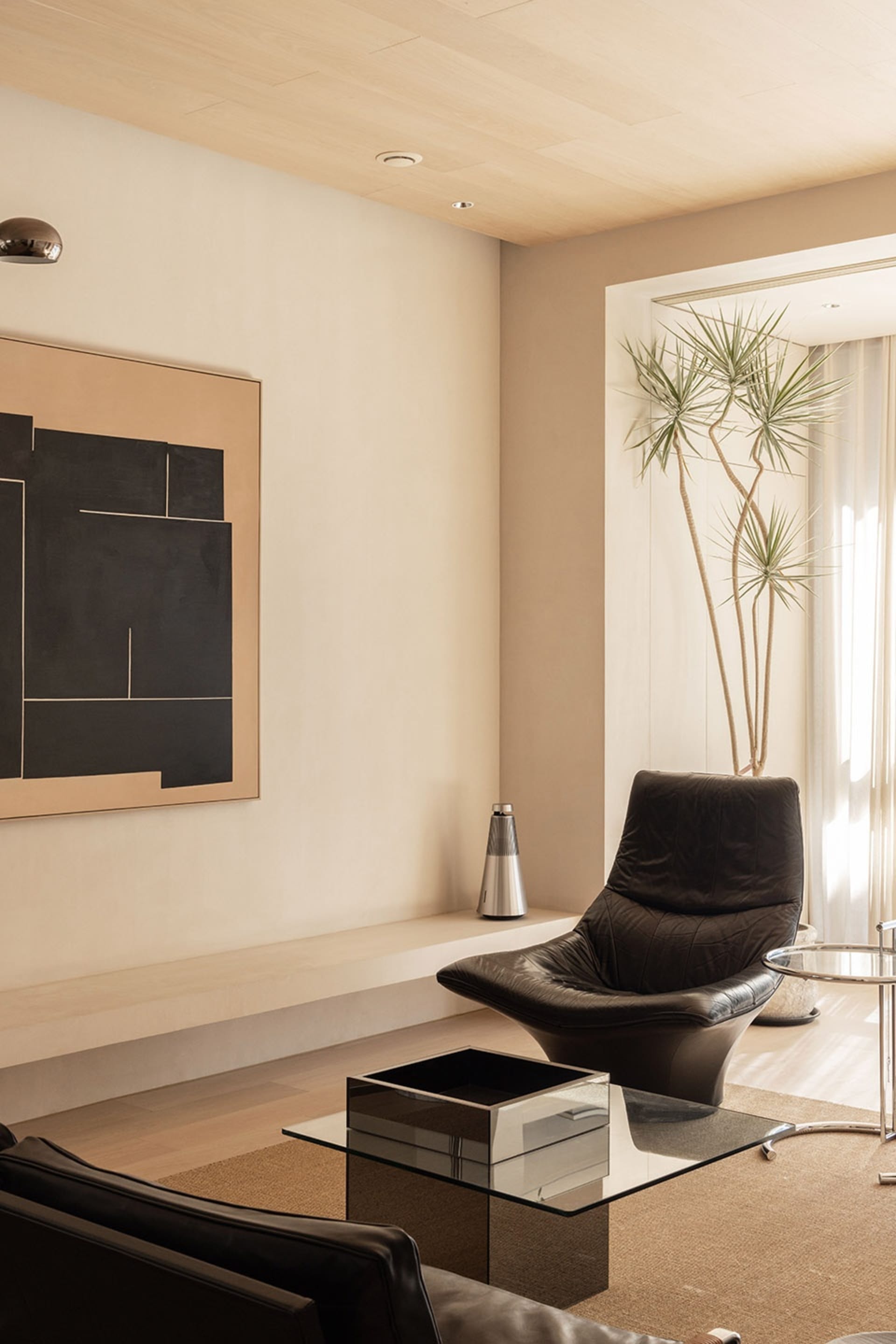 A modern minimalist living room featuring wood, leather, and glass materials.