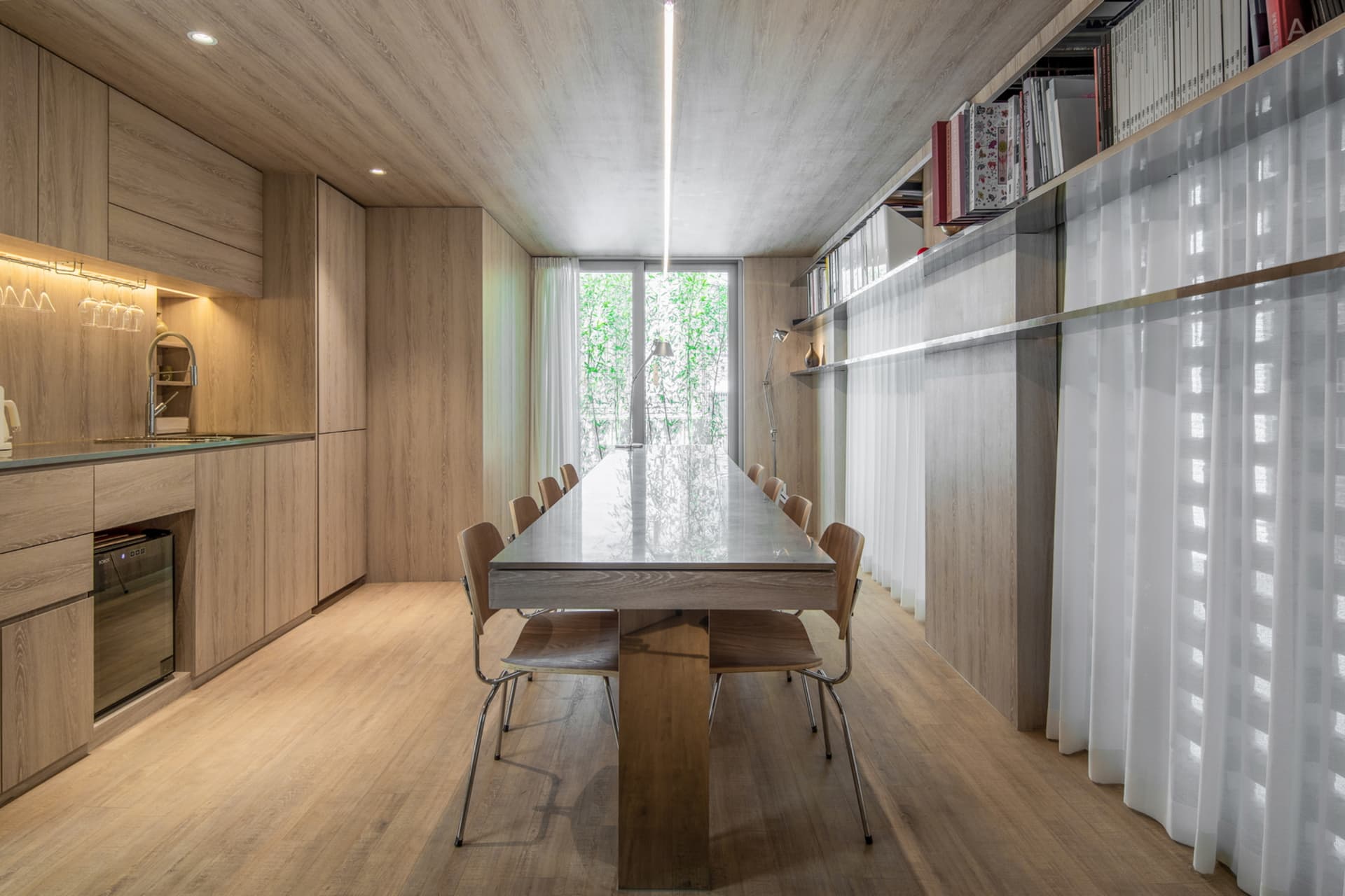 A modern dining room with wooden furniture and a long table.