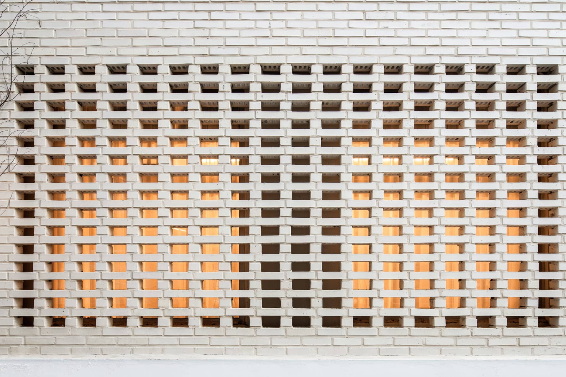 A white brick wall featuring a geometric pattern with alternating solid and transparent bricks.