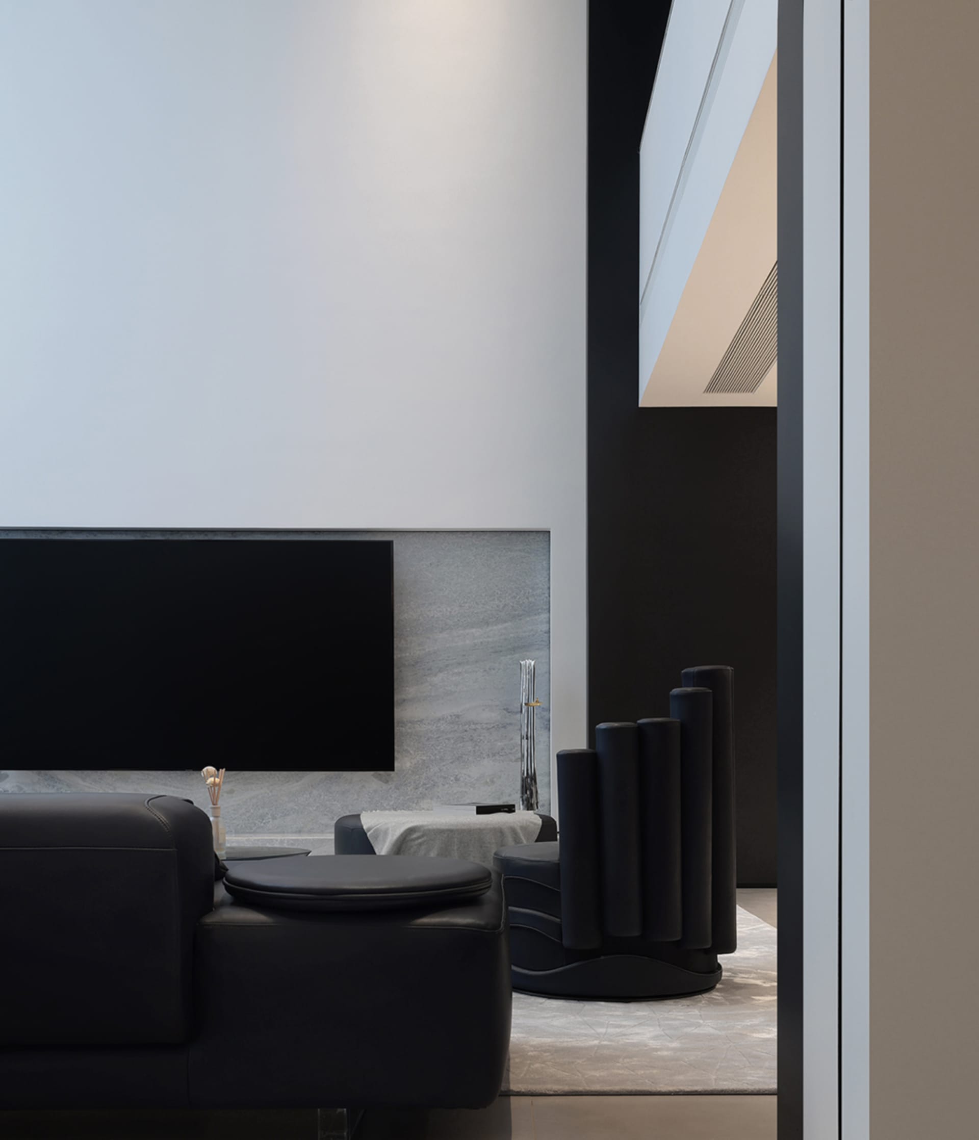 Modern living room featuring black leather furniture and sleek technology elements.