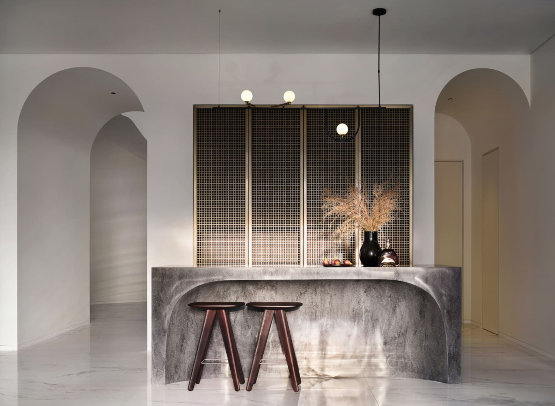 An industrial-style interior with concrete stools and a vase with dry plants on a textured concrete surface.