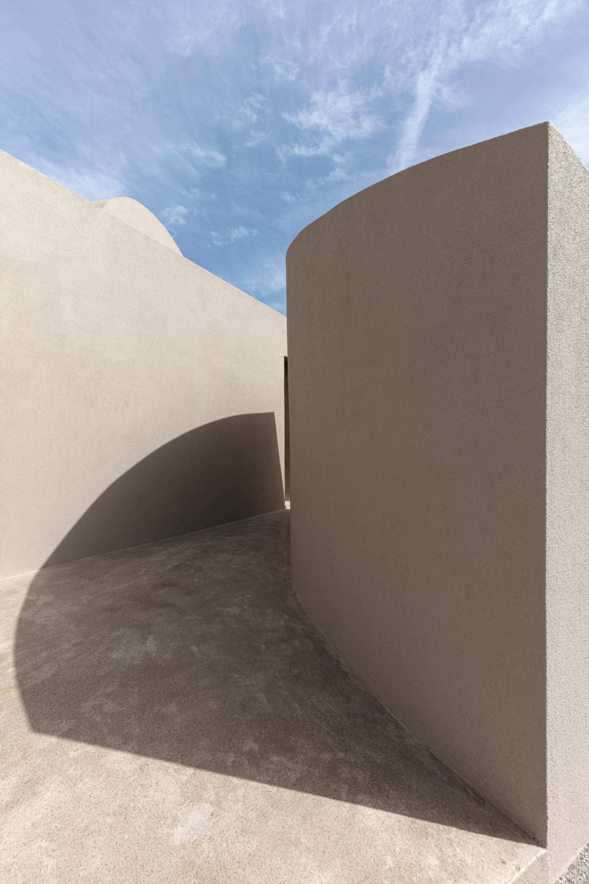Modern concrete architectural design with curved walls and shadows.