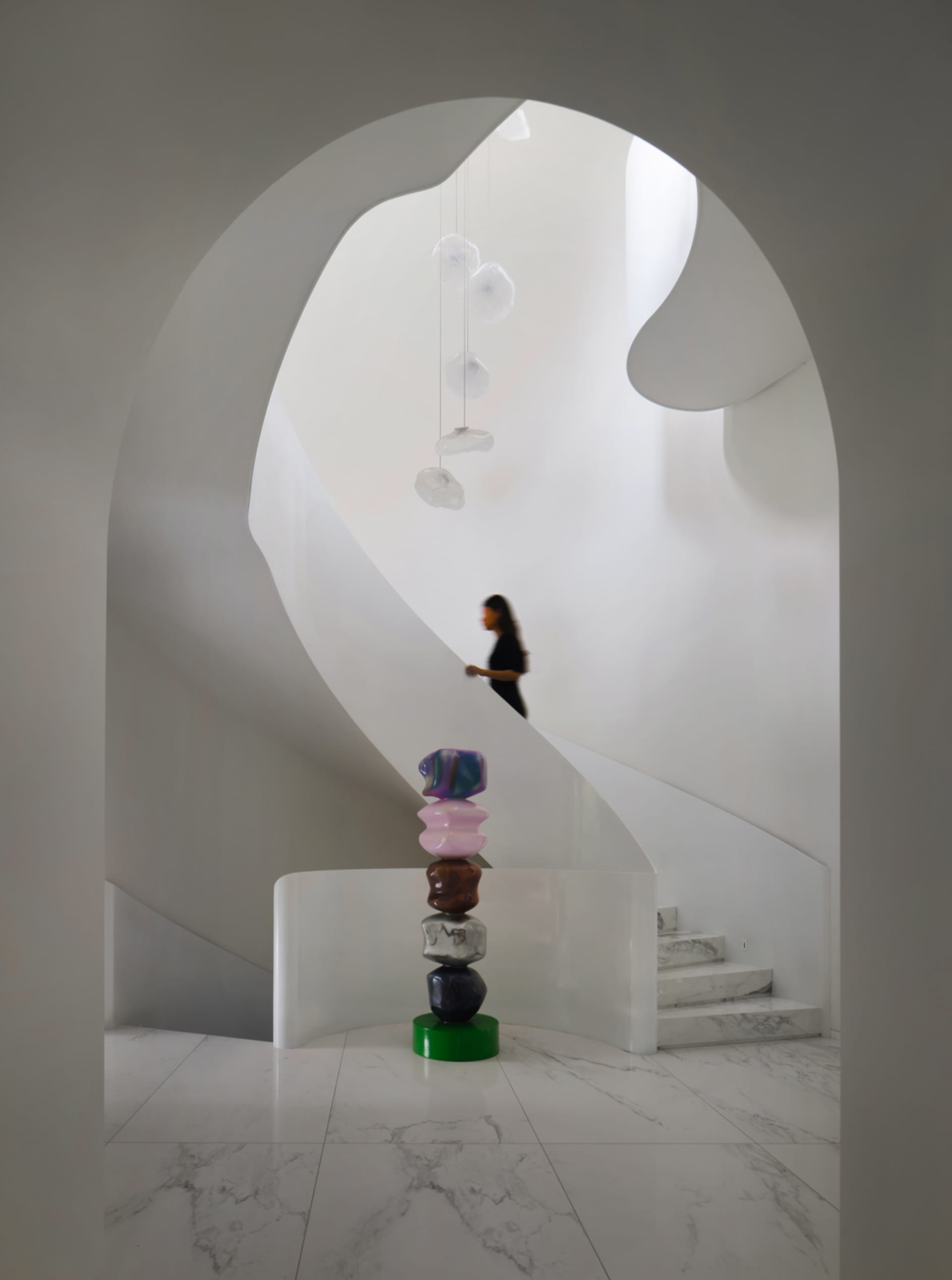 Modern interior design featuring a glass staircase with colorful sculptures and an abstract art installation