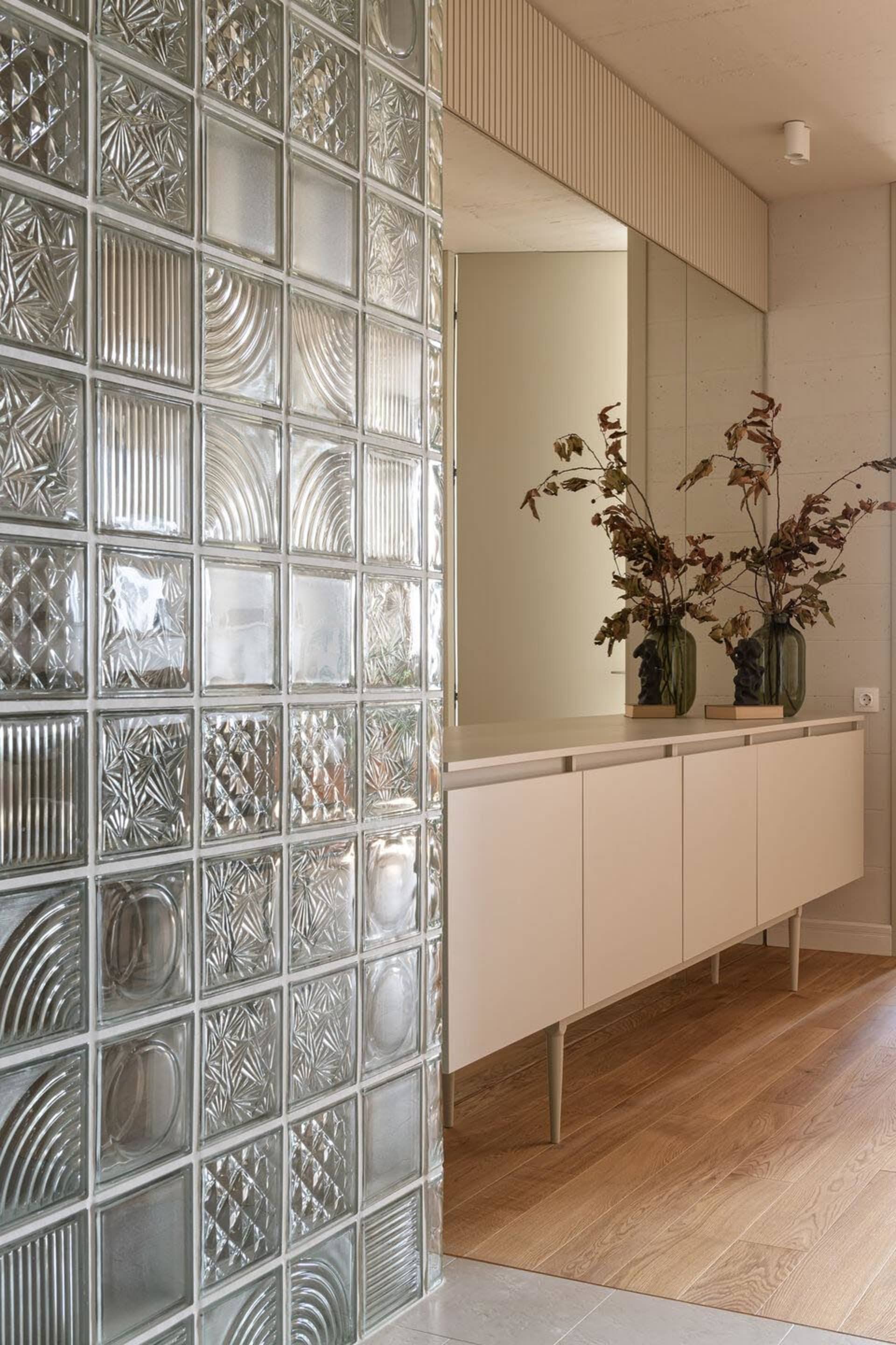 Modern living room featuring a glass block wall with a wooden floor and white cabinets.