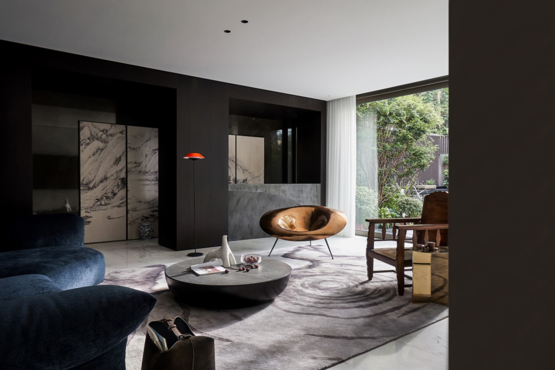 Modern living room featuring a sleek, curved wooden armchair, a round coffee table, and a dark, textured sofa, with large win