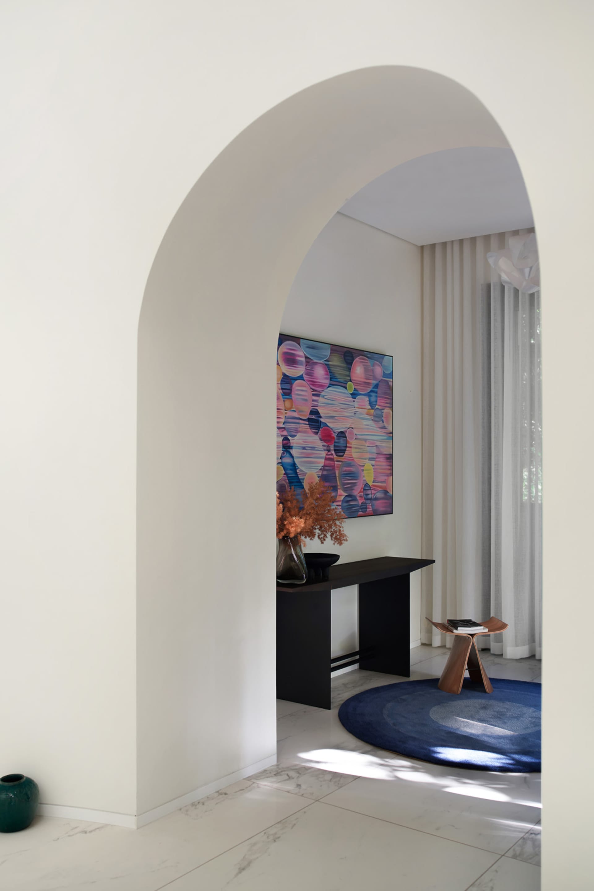 Modern living room with marble floors and decorative seating area.