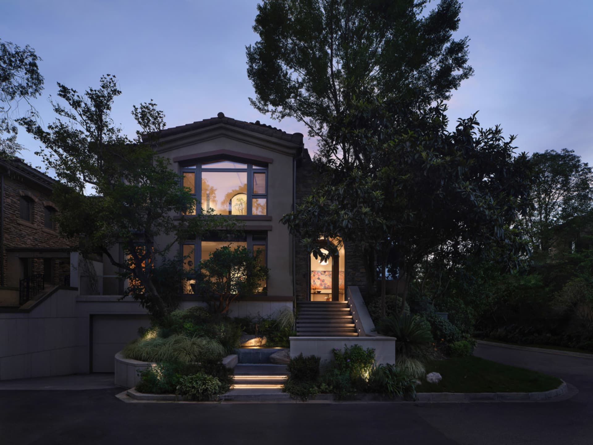A residential faux-bungalow exterior with a tile roof at dusk.