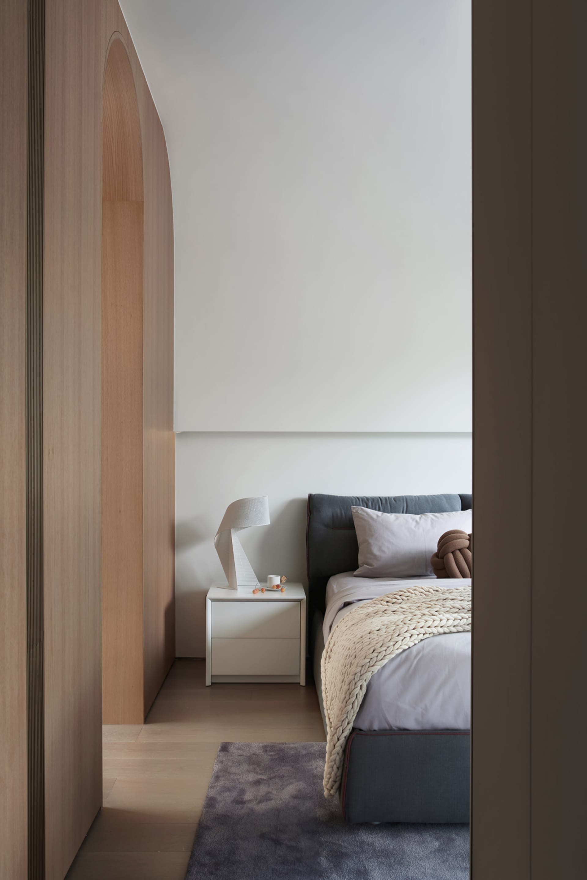 A minimalist bedroom featuring a gray blanket on the bed.