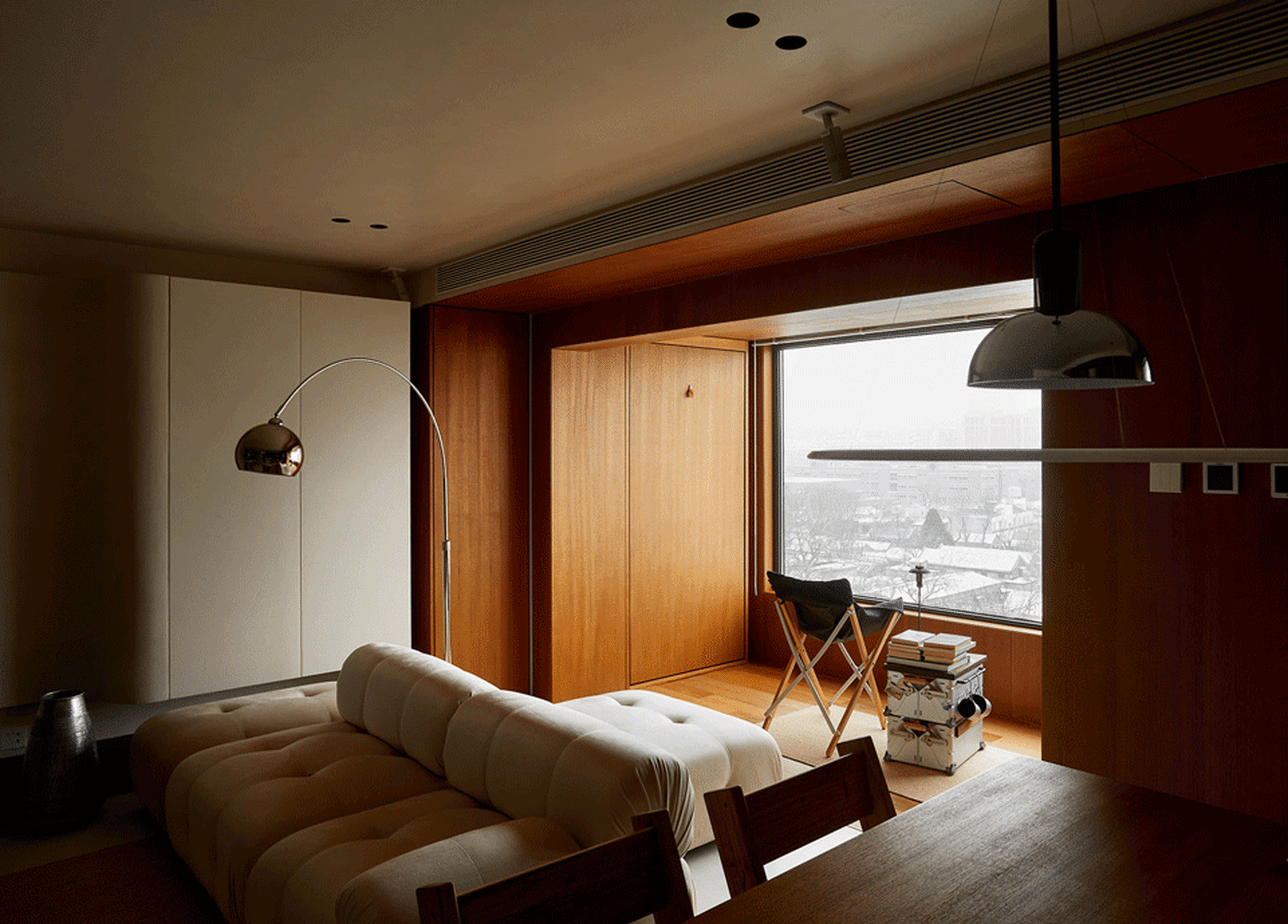 A modern living room with wooden furniture and a large window overlooking a snowy landscape.