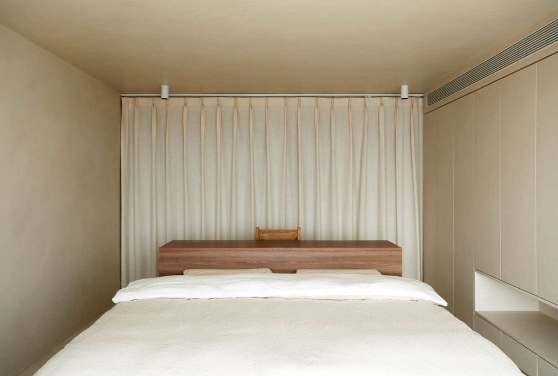 A minimalist bedroom featuring a wooden headboard and curtain.