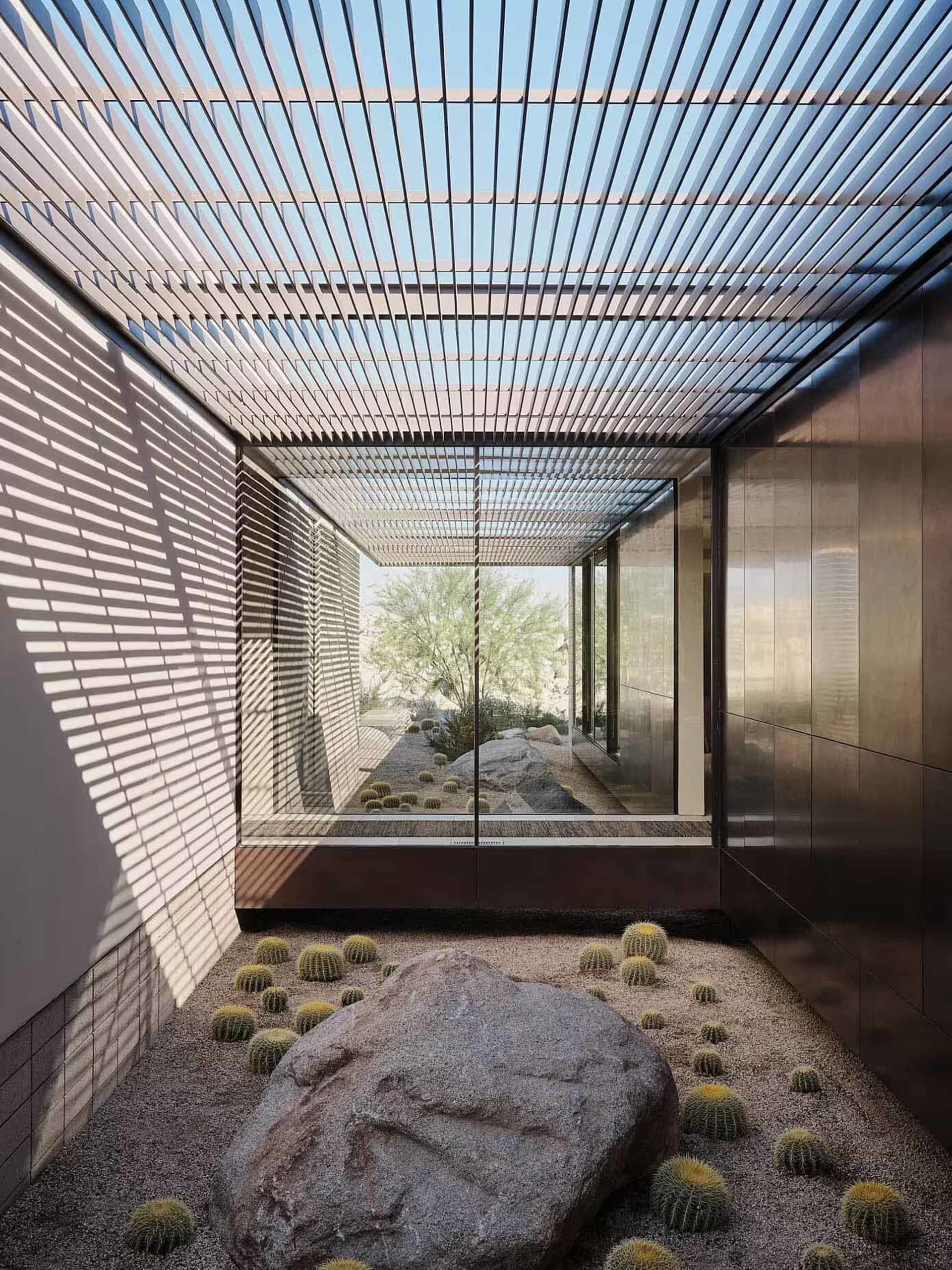 A minimalist glass interior featuring a desert landscape with cacti and rocks.