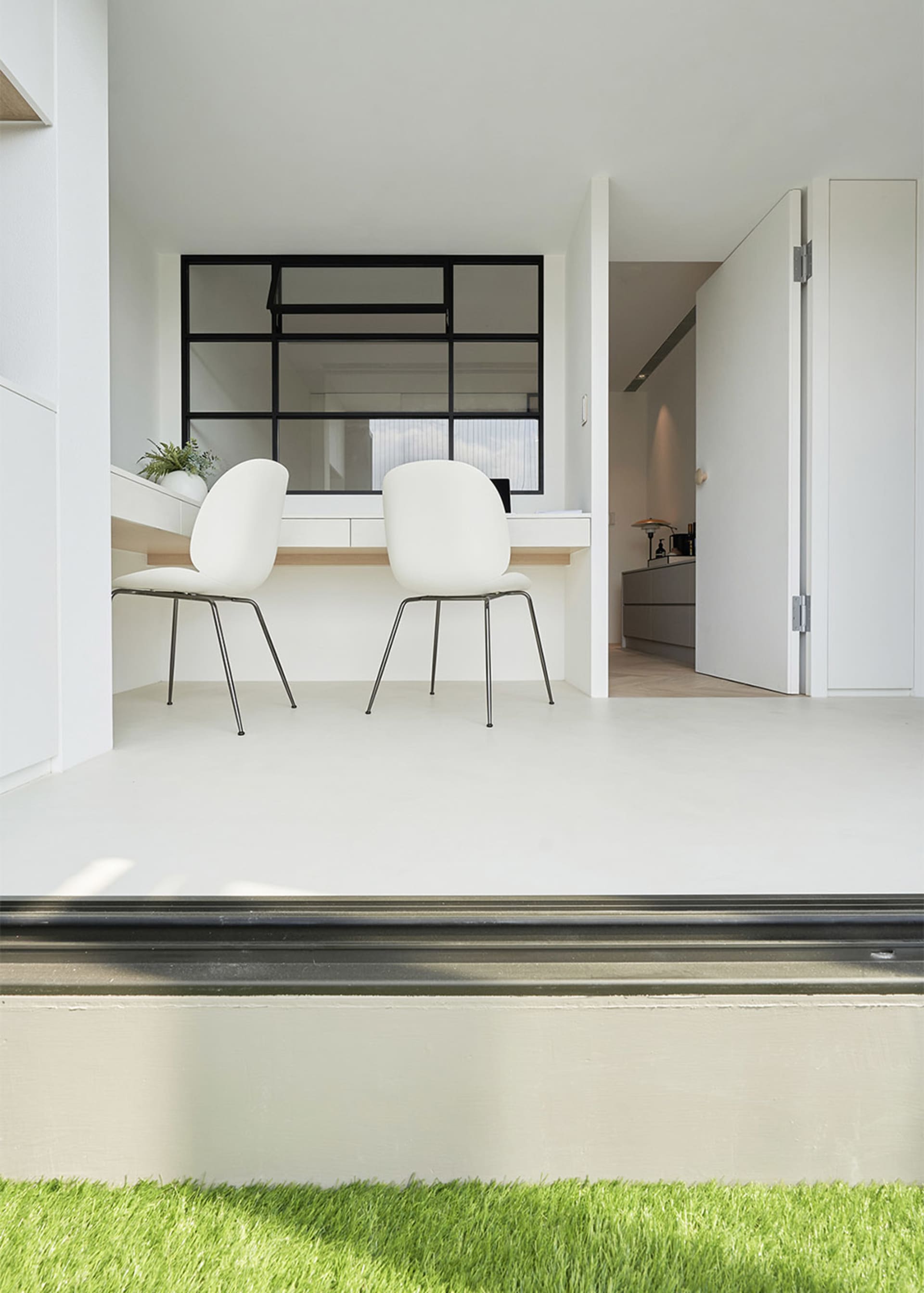 A minimalist home office featuring a sleek, white minimalist desk and chairs with black frames, set against a white backgroun