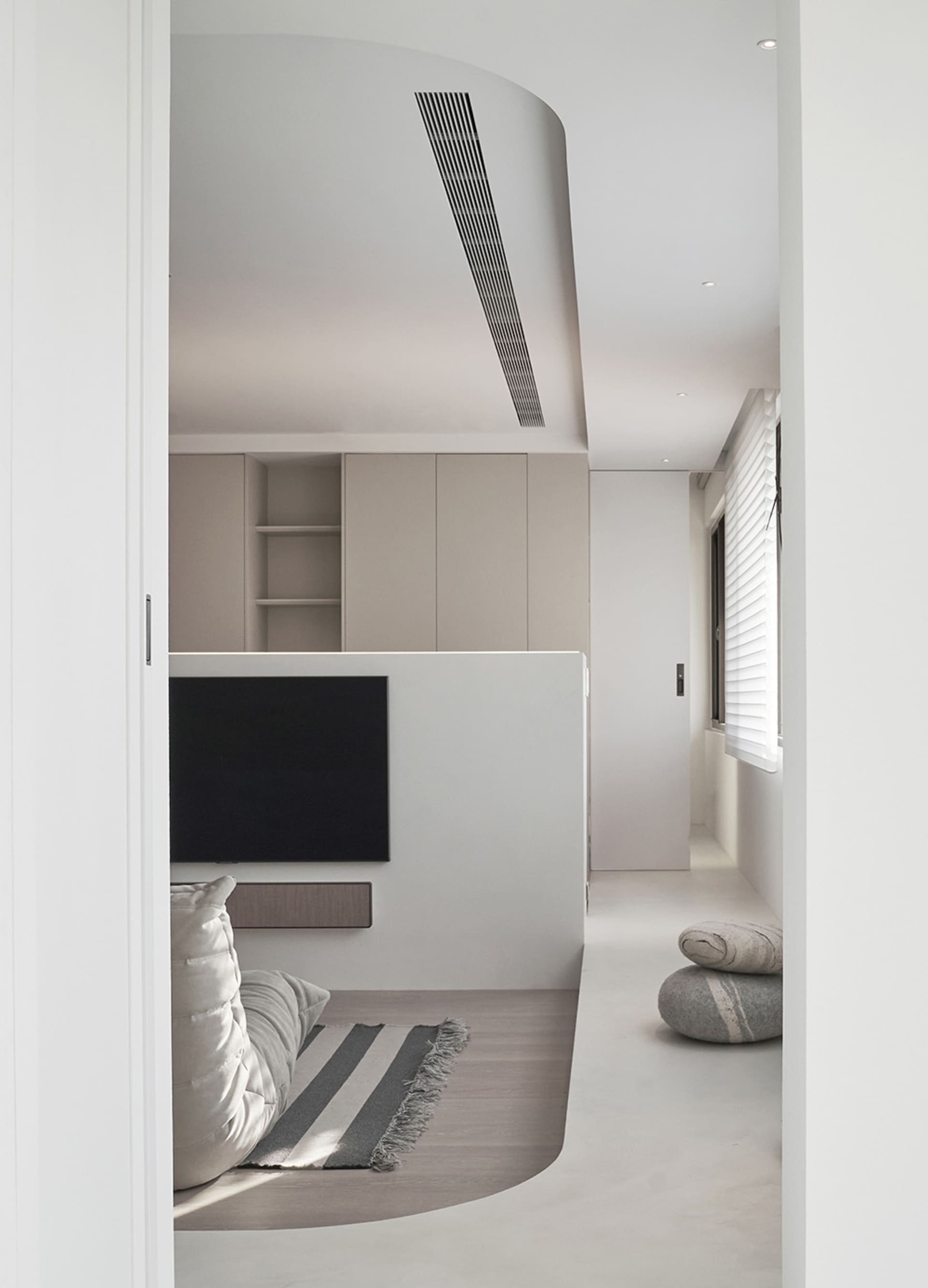 Modern minimalist living room featuring concrete walls and floor, minimalist furniture, and a sleek black TV console.