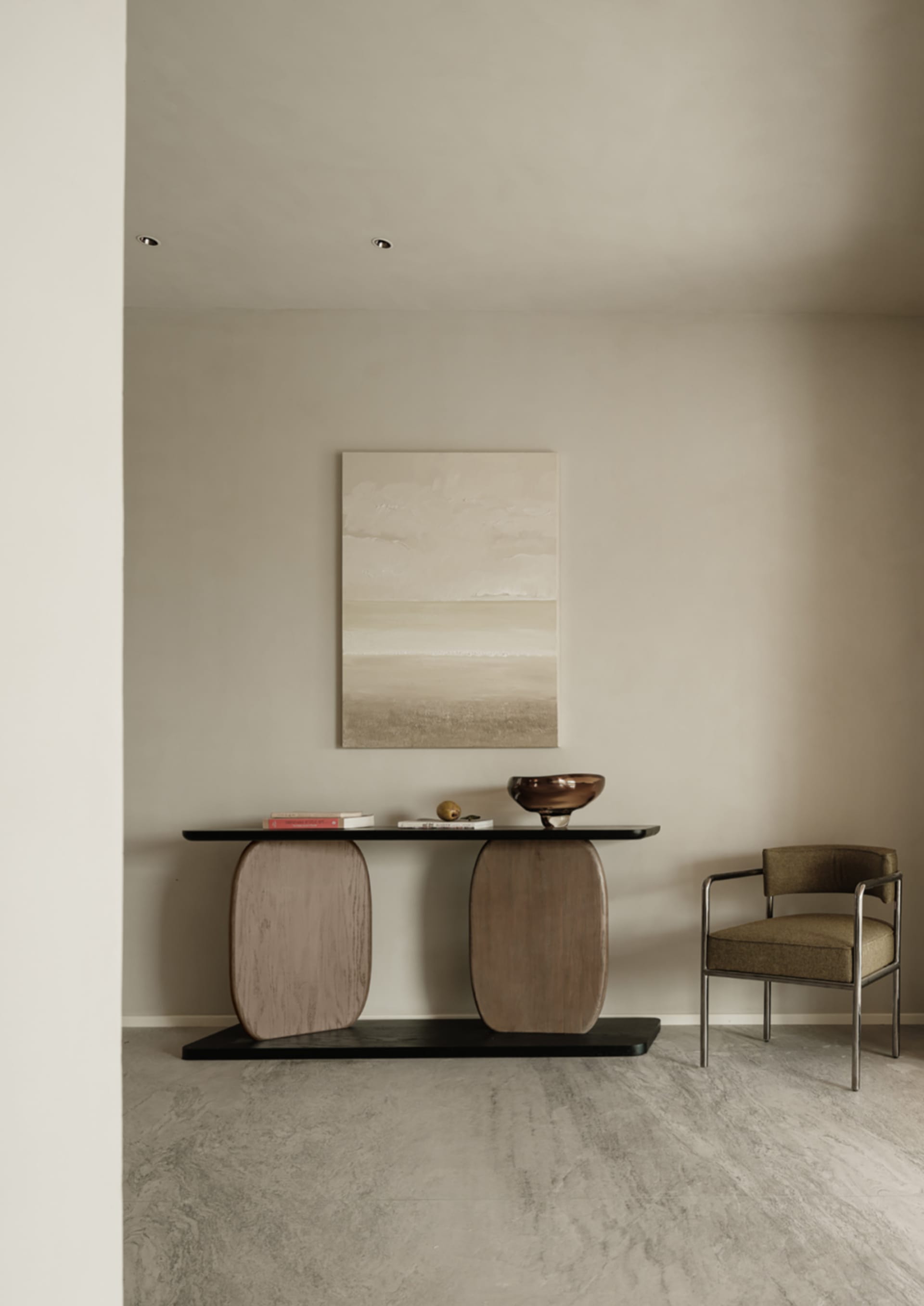 A minimalist living room featuring a console table with organic-shaped wood columns, a black tabletop, and a single brown cha