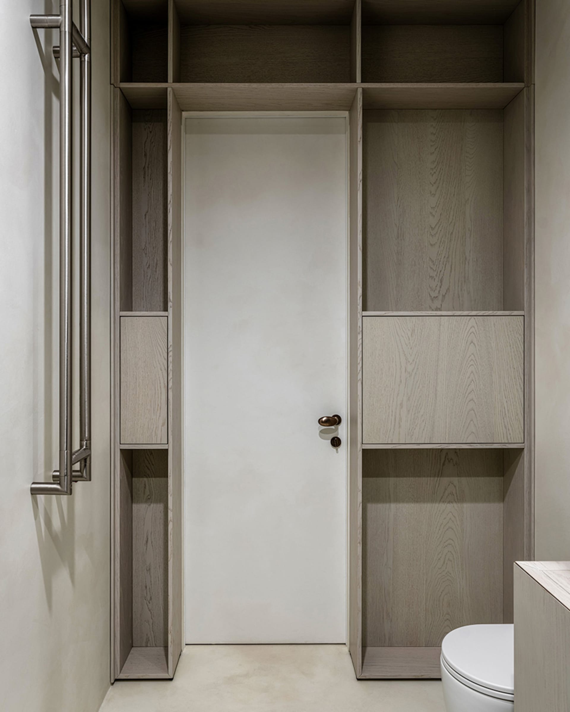 A minimalist bathroom with wooden cabinets and a white door.