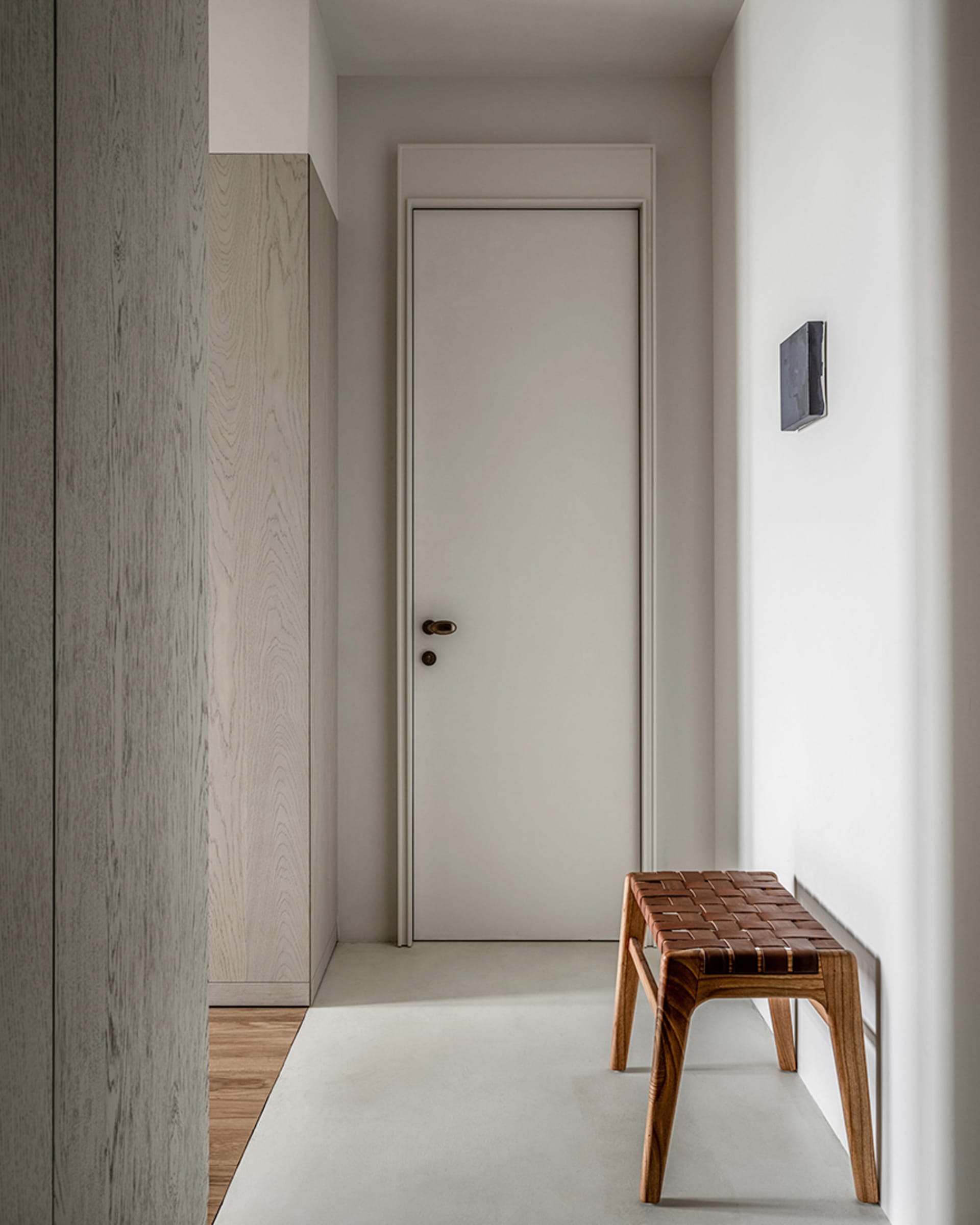 A modern entryway featuring a wooden furniture piece and a closed door.