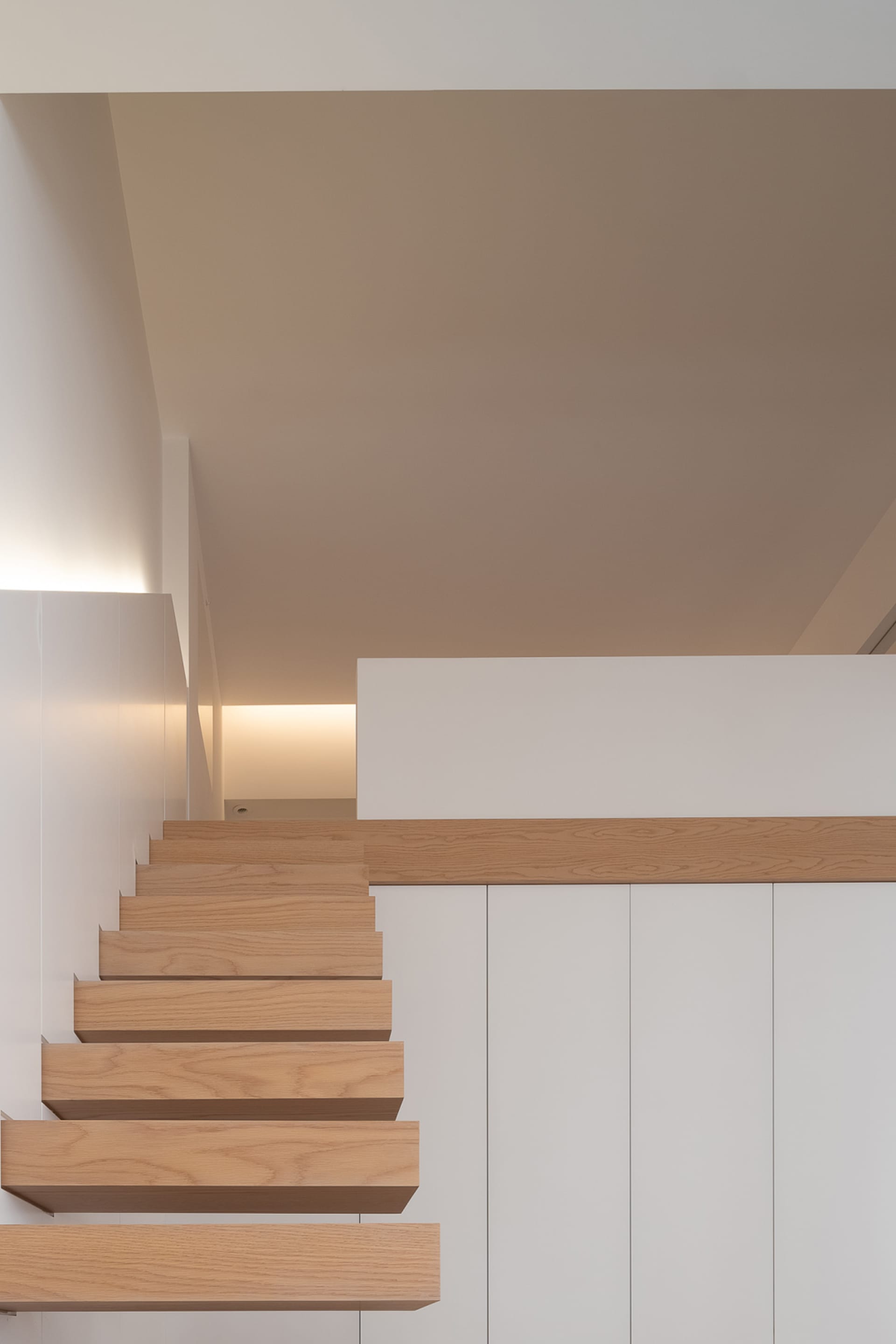Modern interior design featuring wooden stairs and white walls.