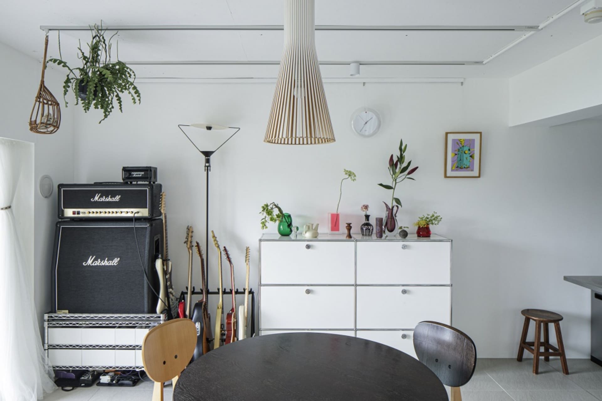 A modern music studio with minimalist design, featuring metallic elements, glass paneling, wooden furniture, and fabric acous