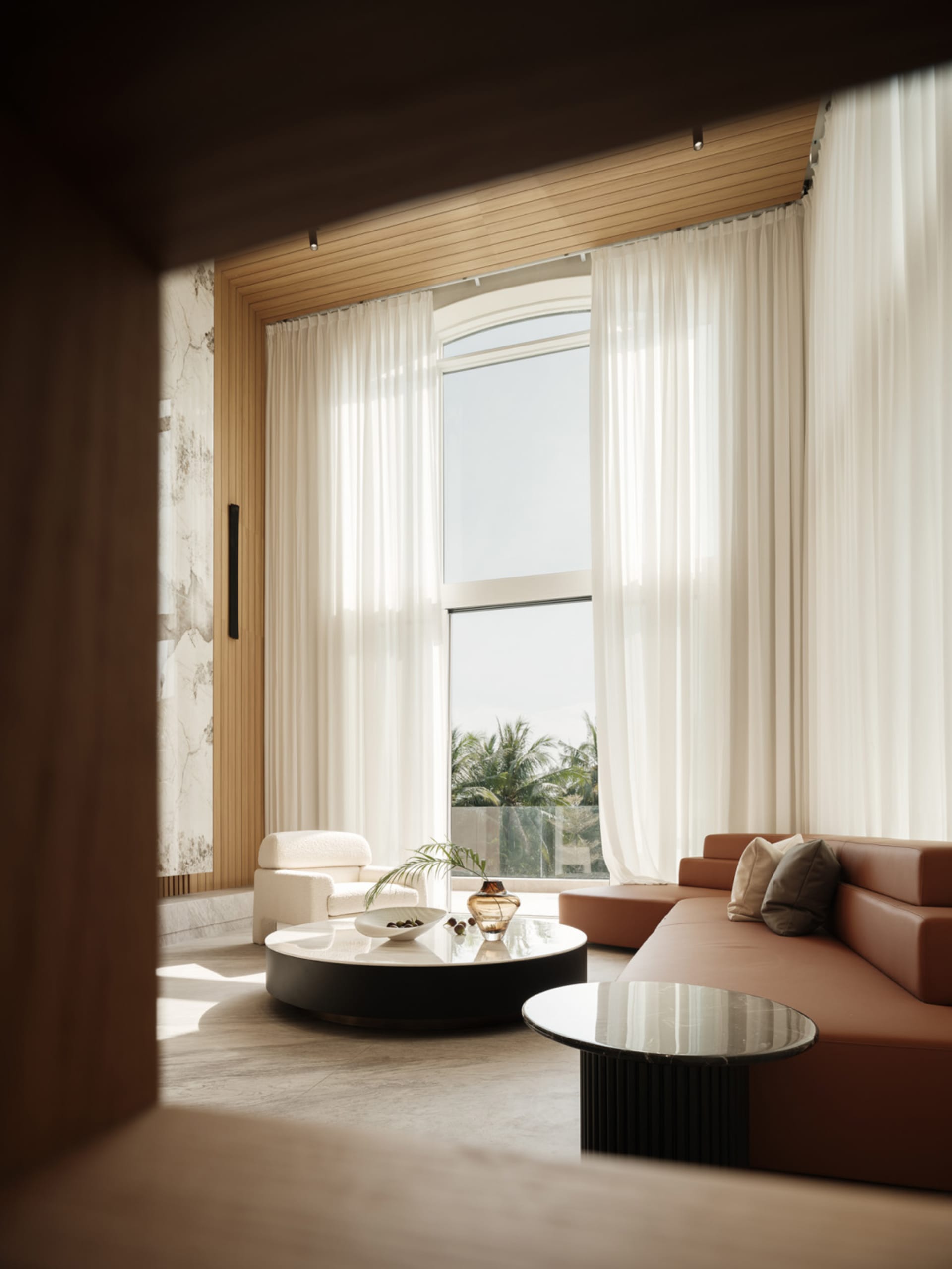 Modern living room with transparent curtains, leather sofa, and marble coffee table.