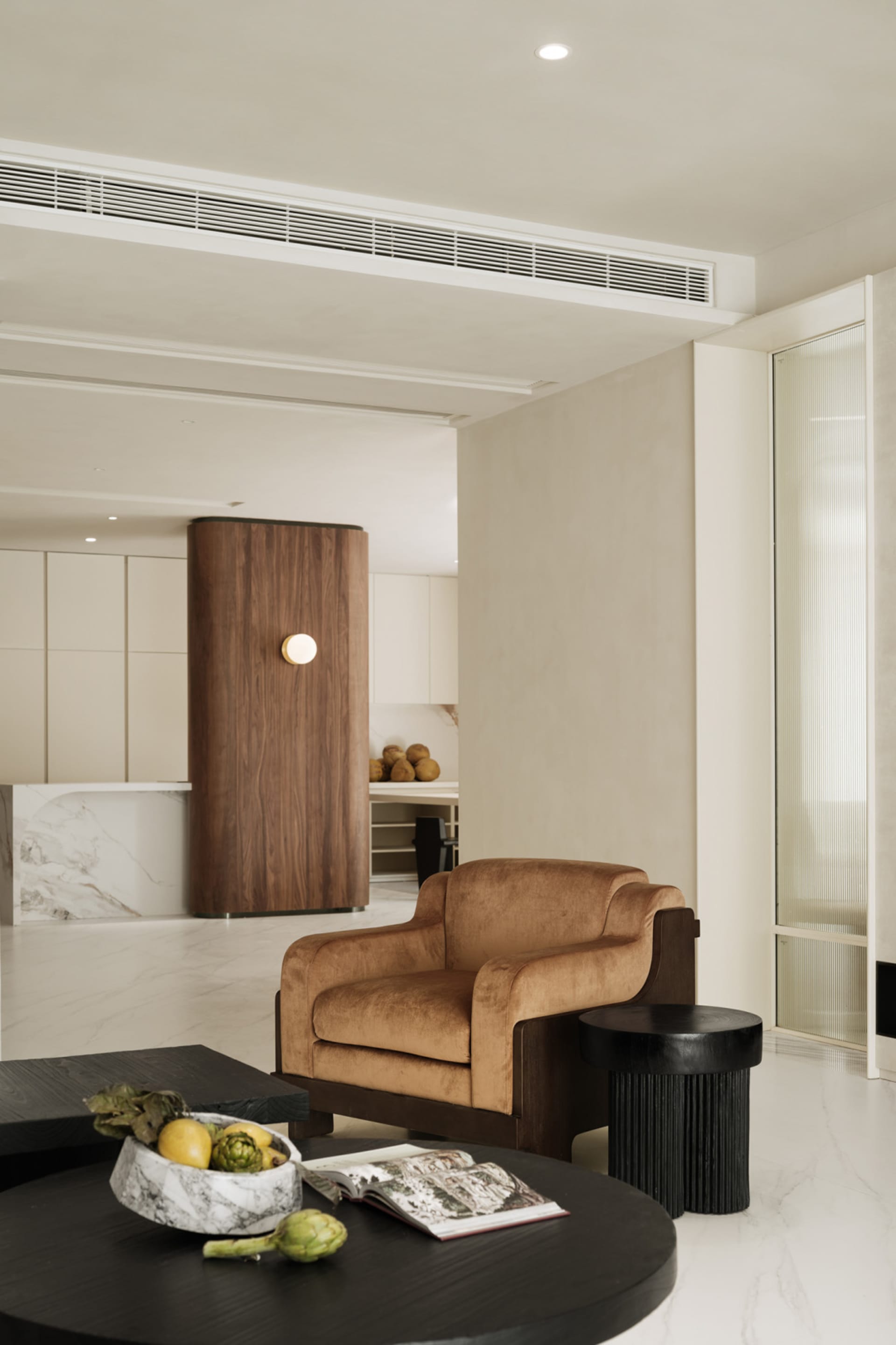 A modern living room with a sand brown leather couch, black round coffee table, and minimalist decor.
