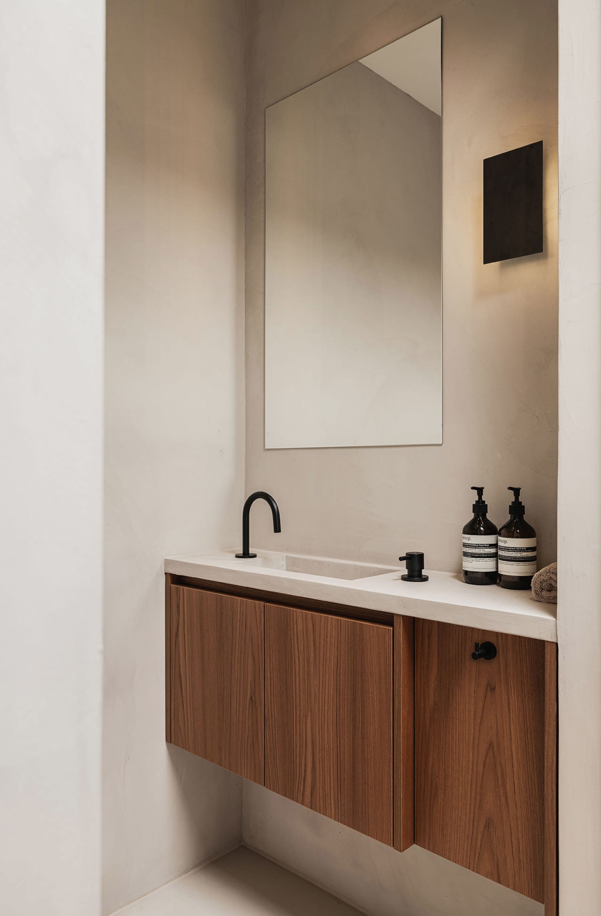 Sunlit modern bathroom with concrete sink, wooden cabinets, and a minimalist design.