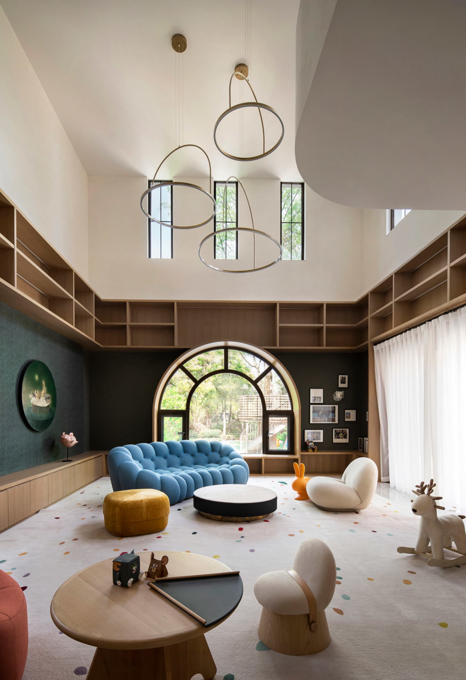 A modern living room featuring a blue sofa, round tables, and glass windows.